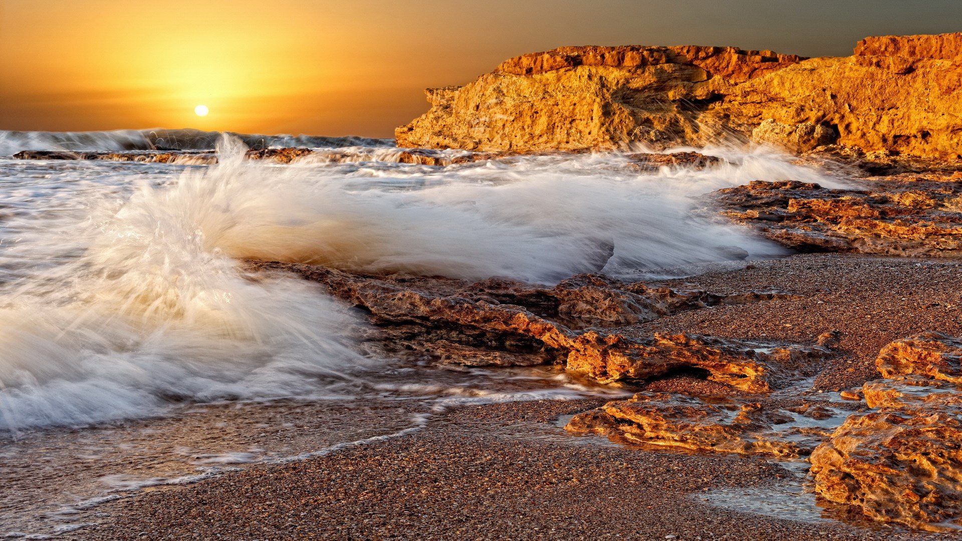 Sunset over rocky beach with crashing waves HD Wallpaper