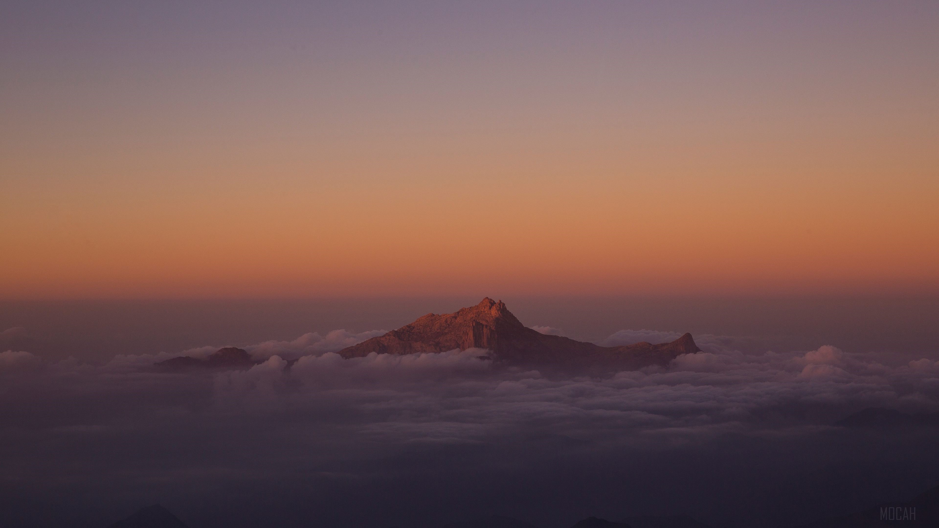 Mountain peak emerging from clouds at sunset 4K HD Wallpaper