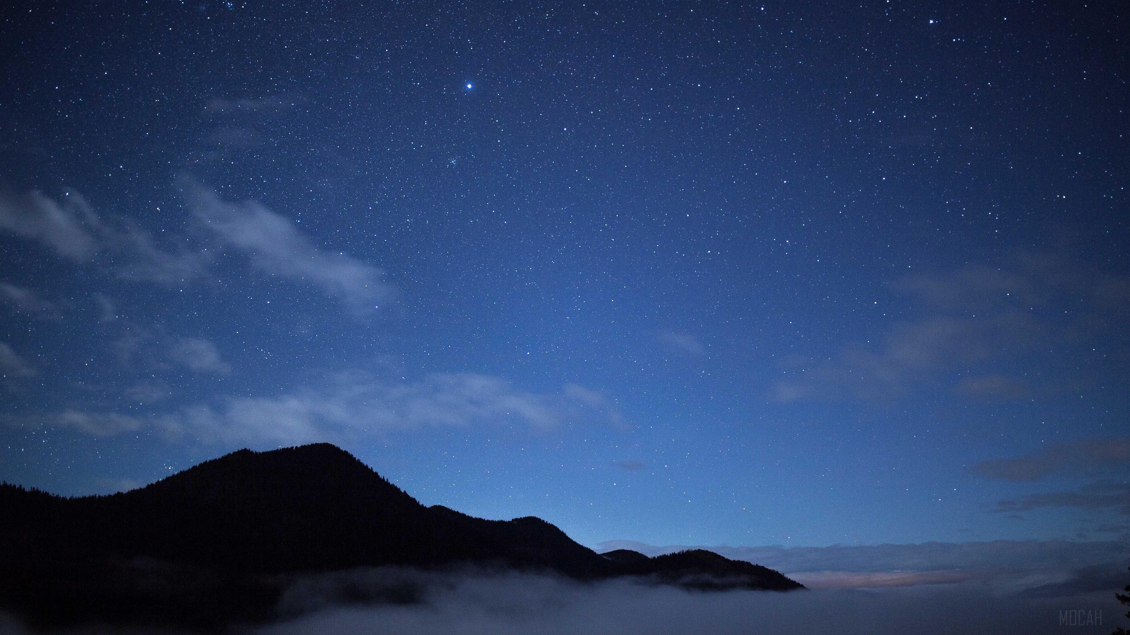 Night sky with stars and clouds over mountains HD Wallpaper
