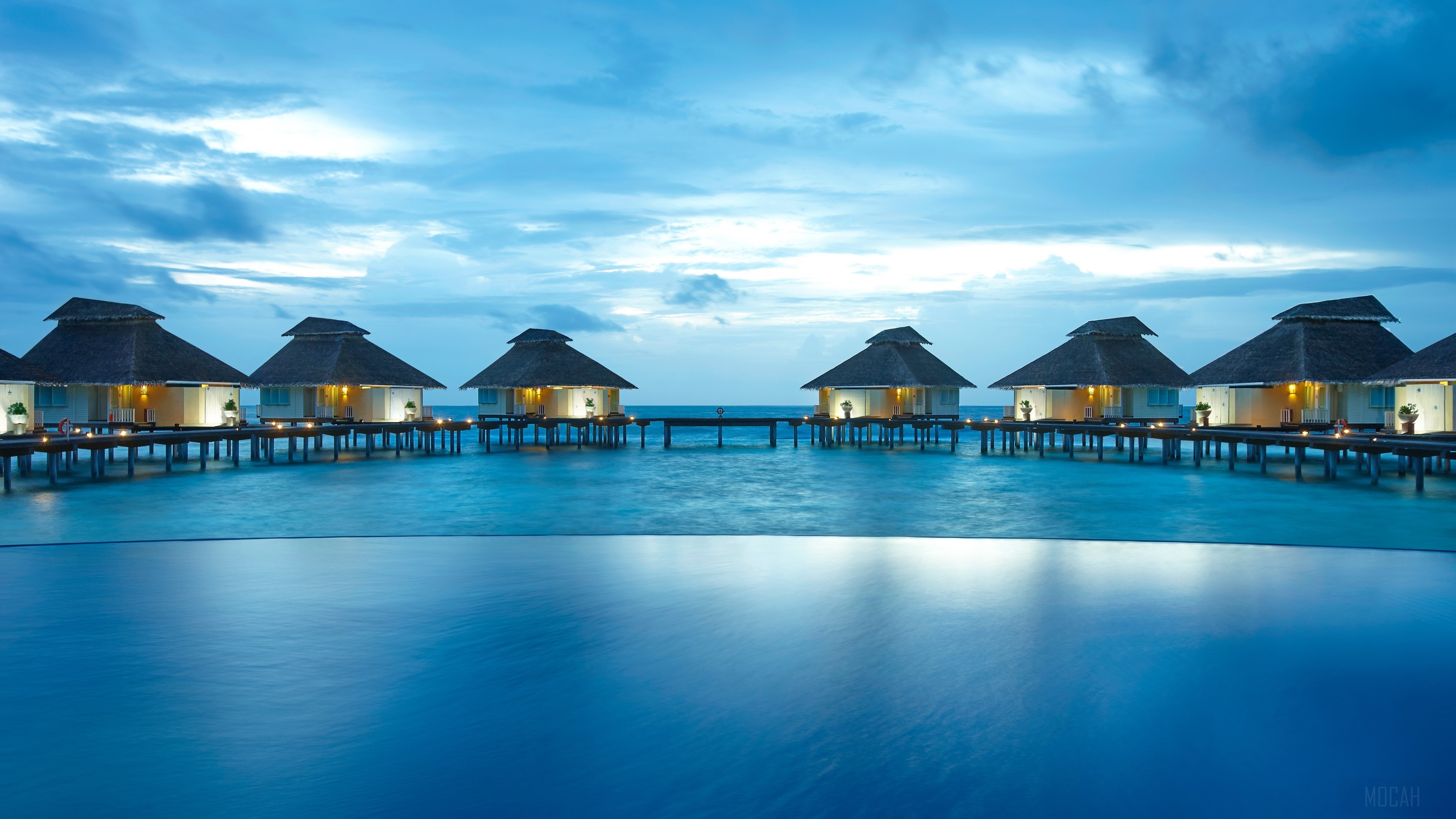 Overwater bungalows at sunset with infinity pool HD Wallpaper