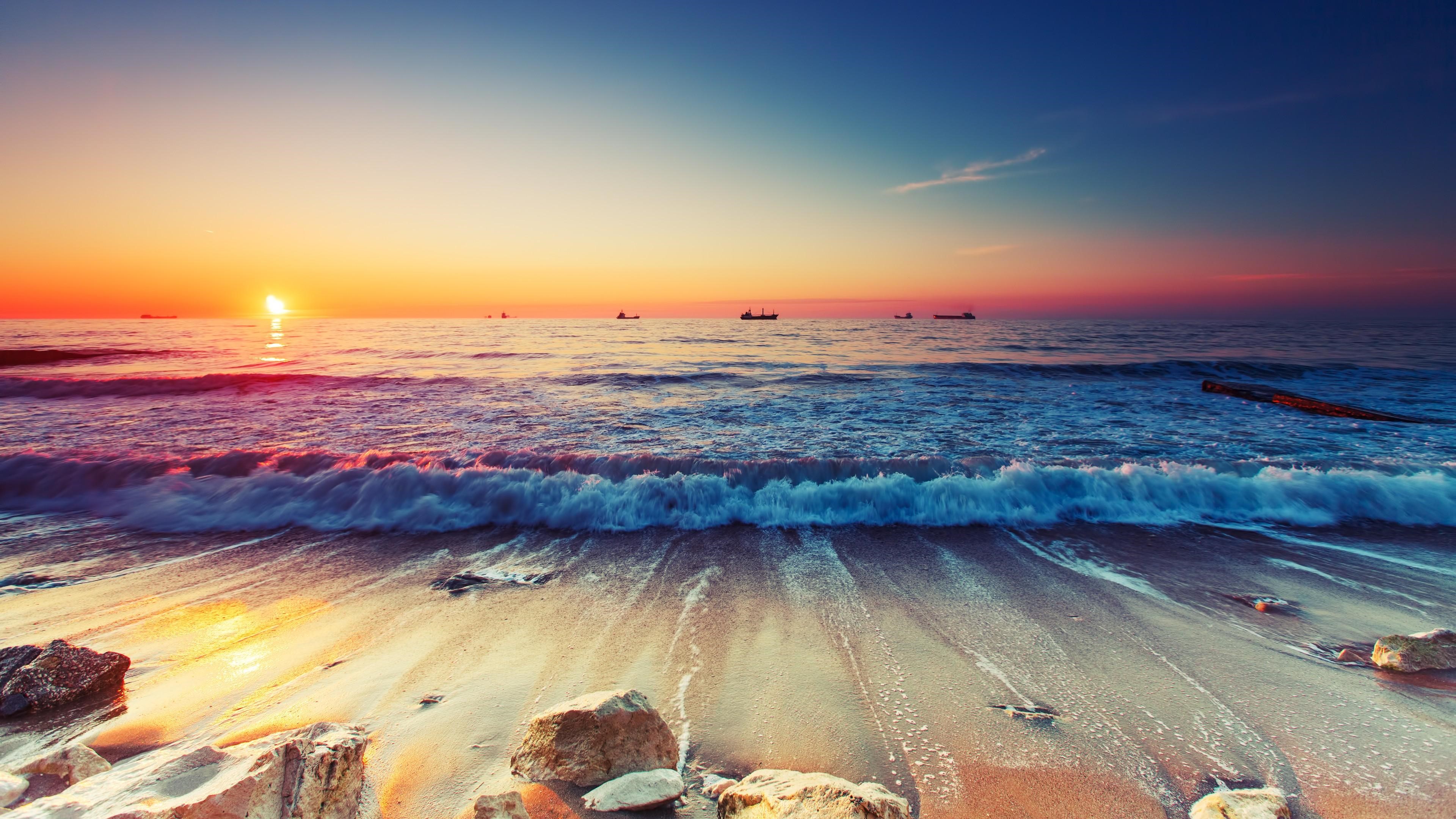 Sunset over the ocean with waves and ships HD Wallpaper
