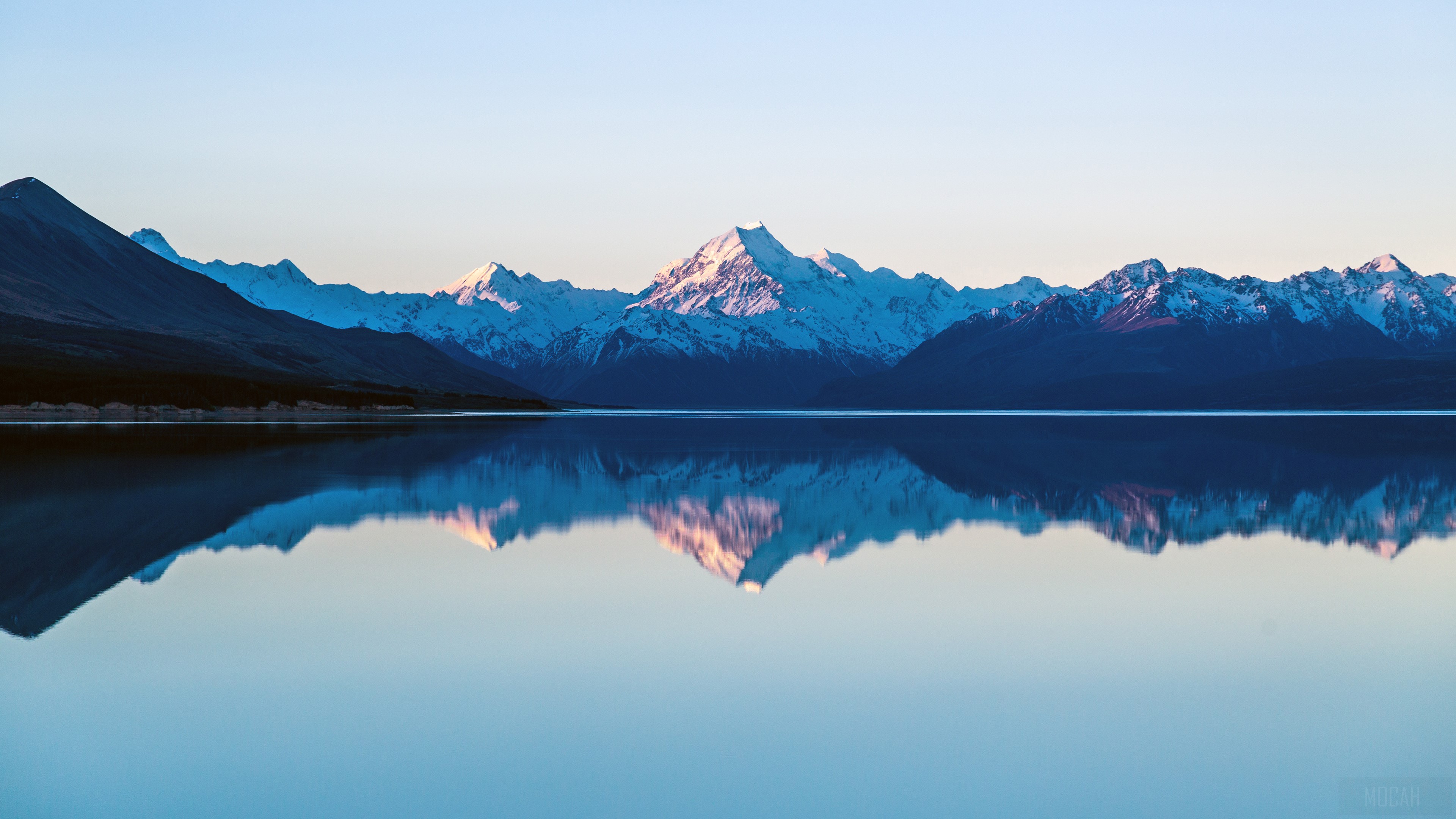 Snow-capped mountains reflected in a calm lake HD Wallpaper