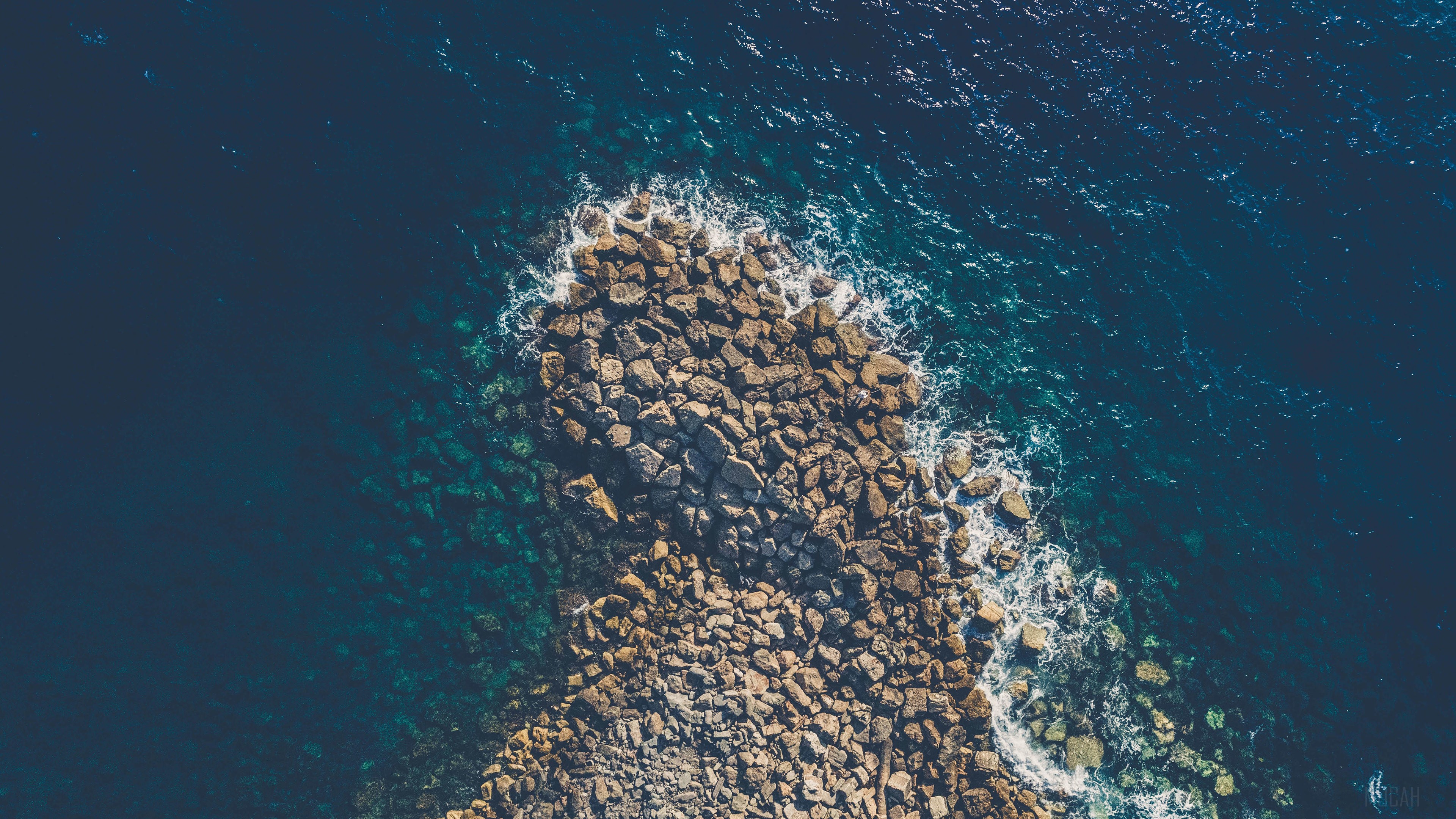 Aerial View of Rocky Coastline and Deep Blue Sea 4K HD Wallpaper