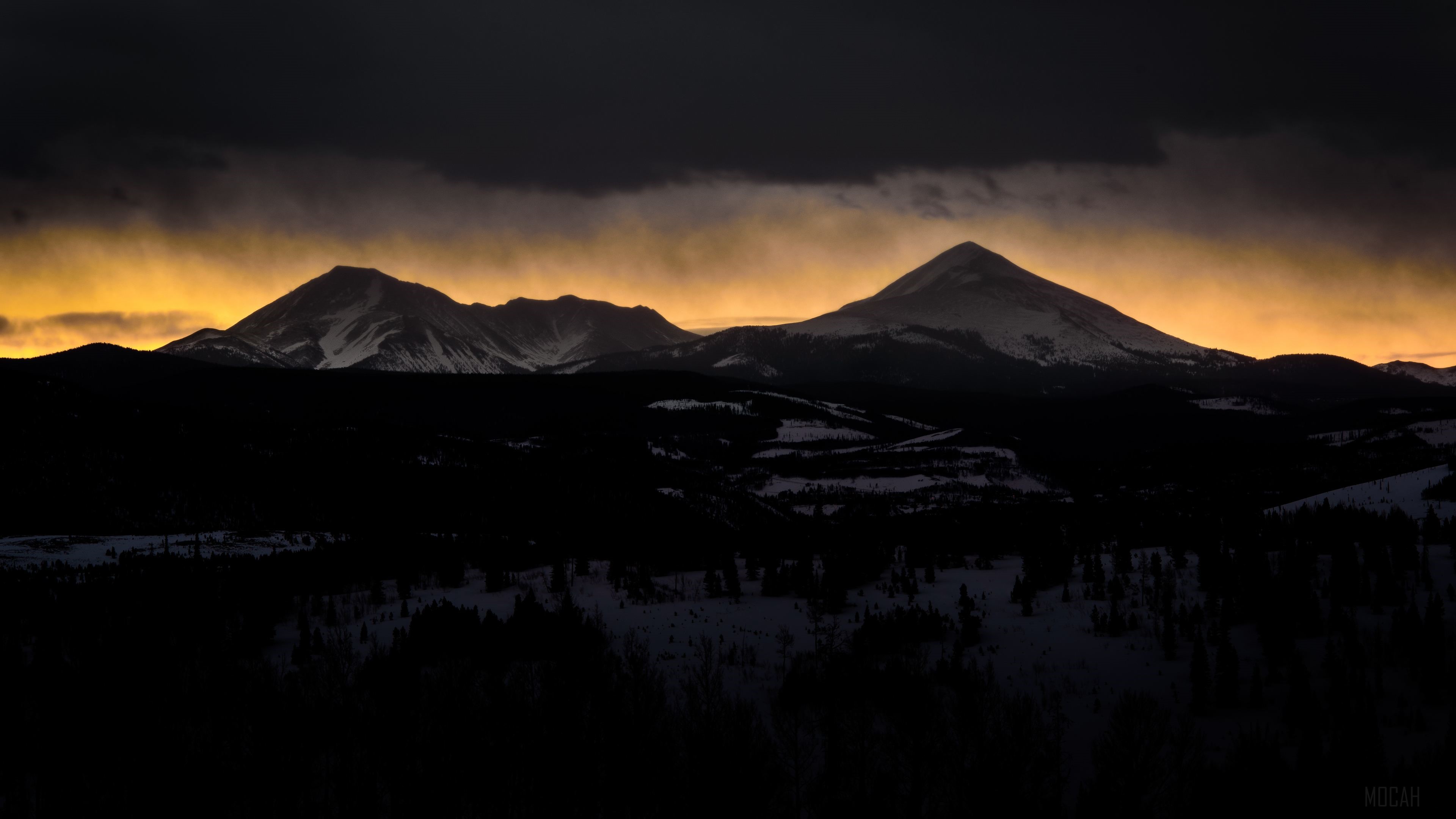 Mountain Range Under Dark Clouds and Golden Light 4K HD Wallpaper