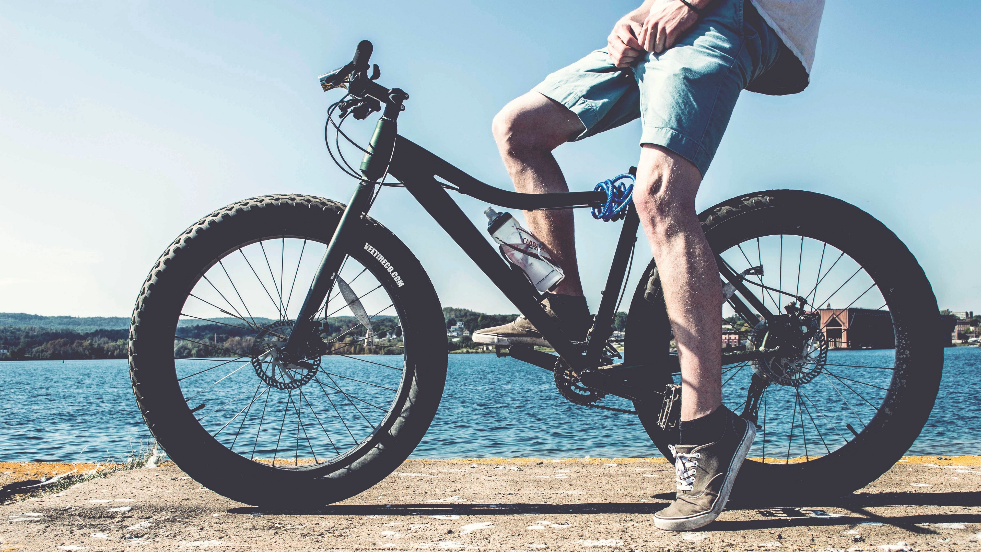 Cyclist on a fat tire bicycle by a river HD Wallpaper