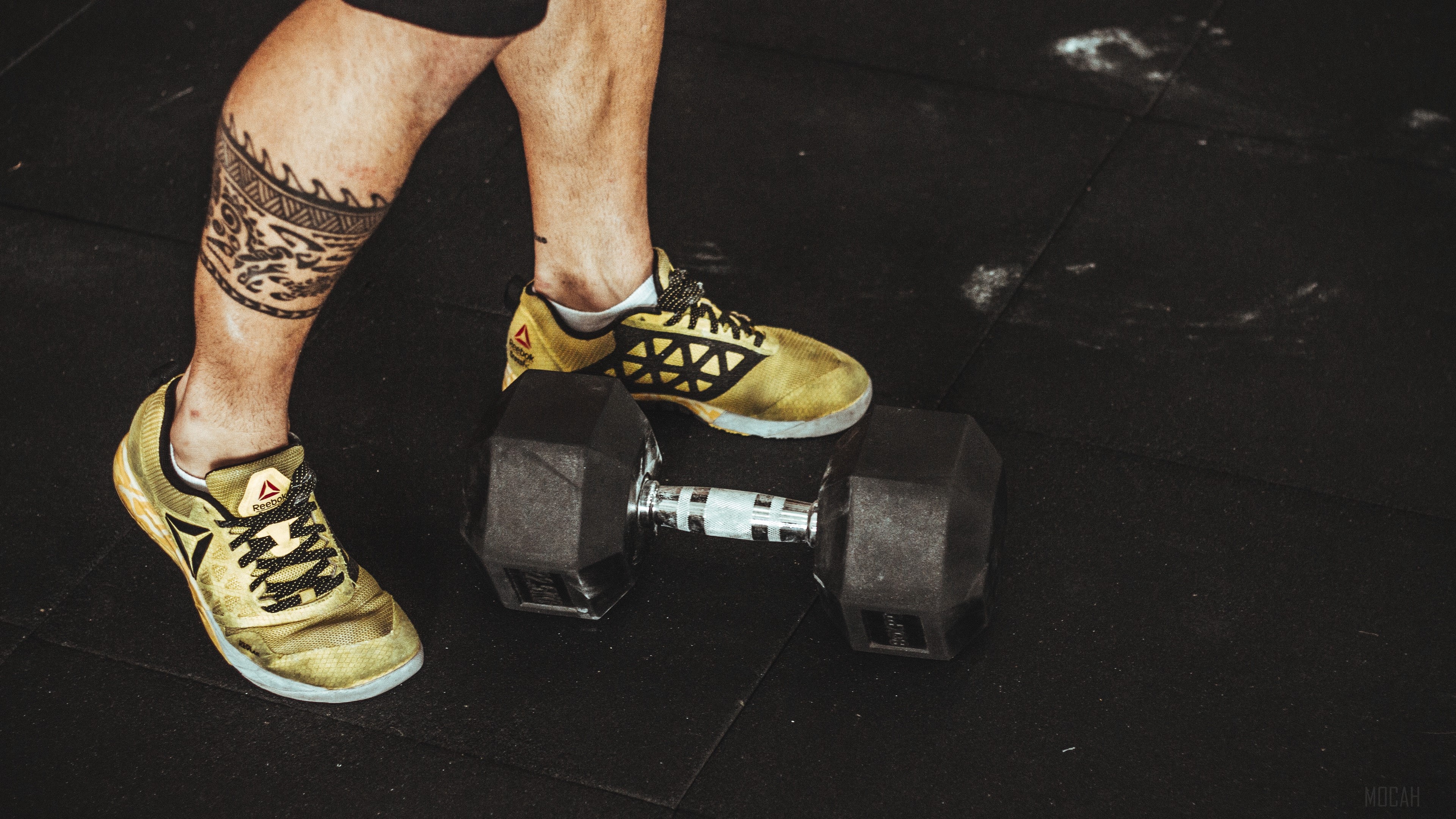 Man's legs with tattoo and Reebok shoes on dumbbell HD Wallpaper