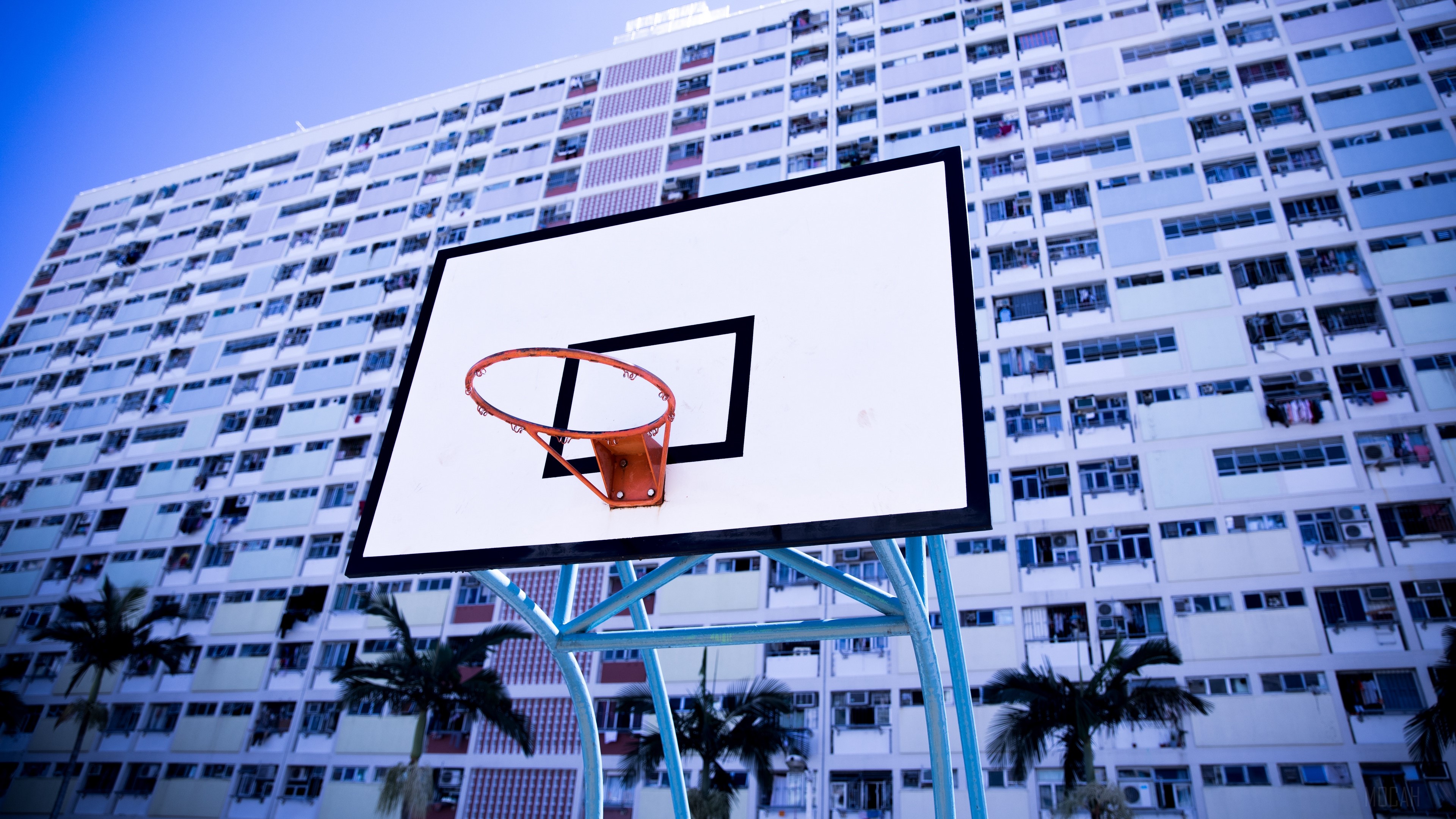 Basketball hoop in front of a tall apartment building HD Wallpaper