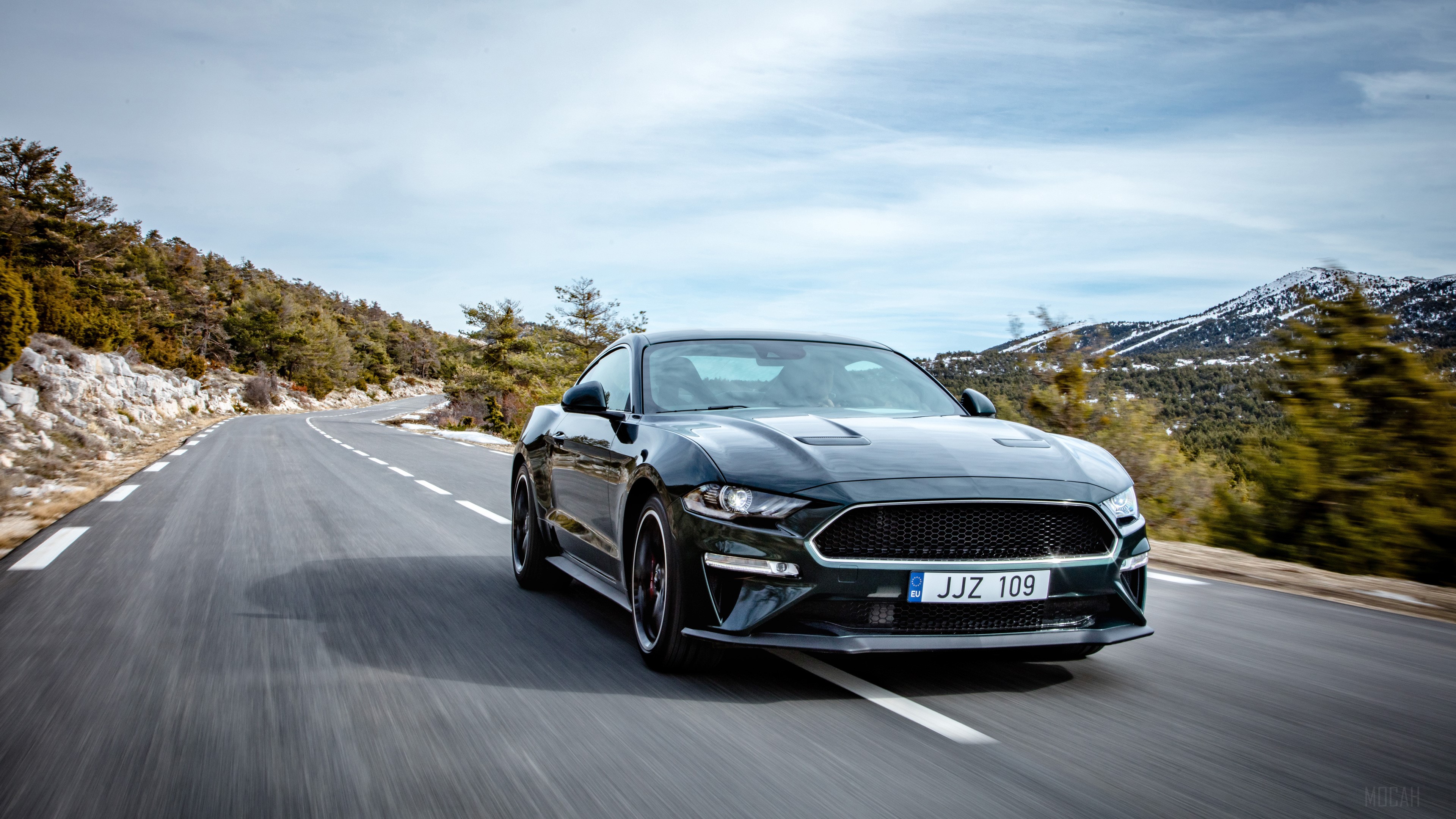 2019 Ford Mustang Bullitt driving on a mountain road HD Wallpaper