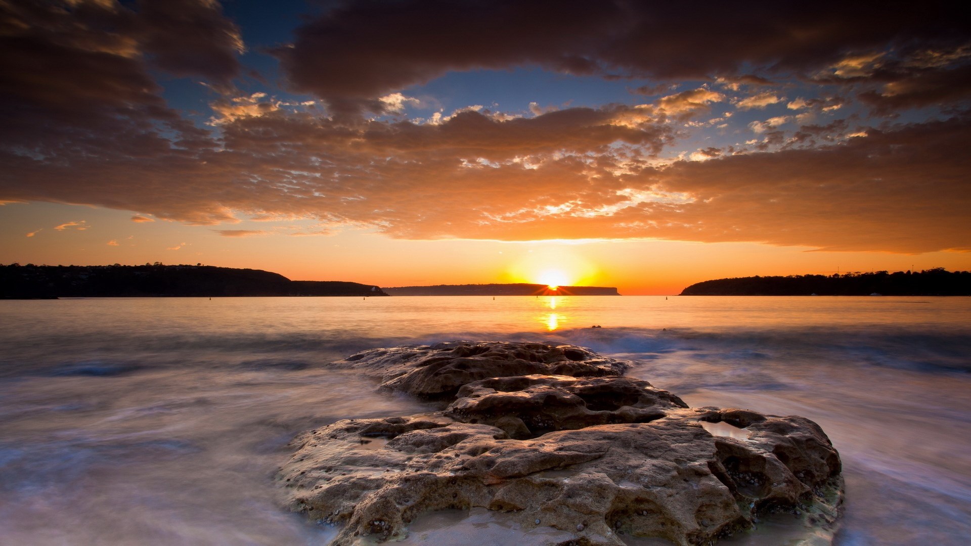 Sunset over the ocean with rocks in the foreground HD Wallpaper