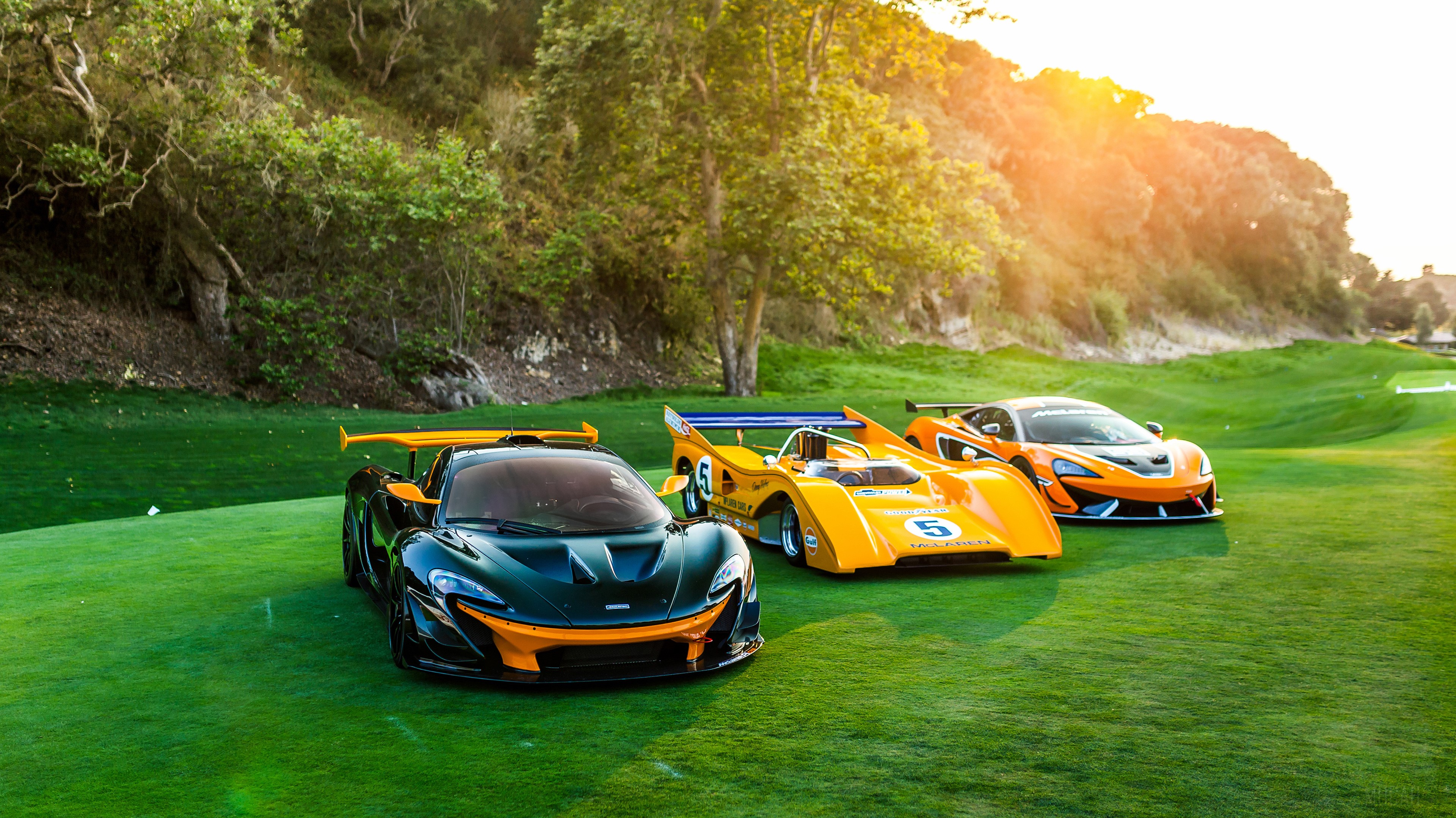 Three McLaren sports cars on a golf course HD Wallpaper