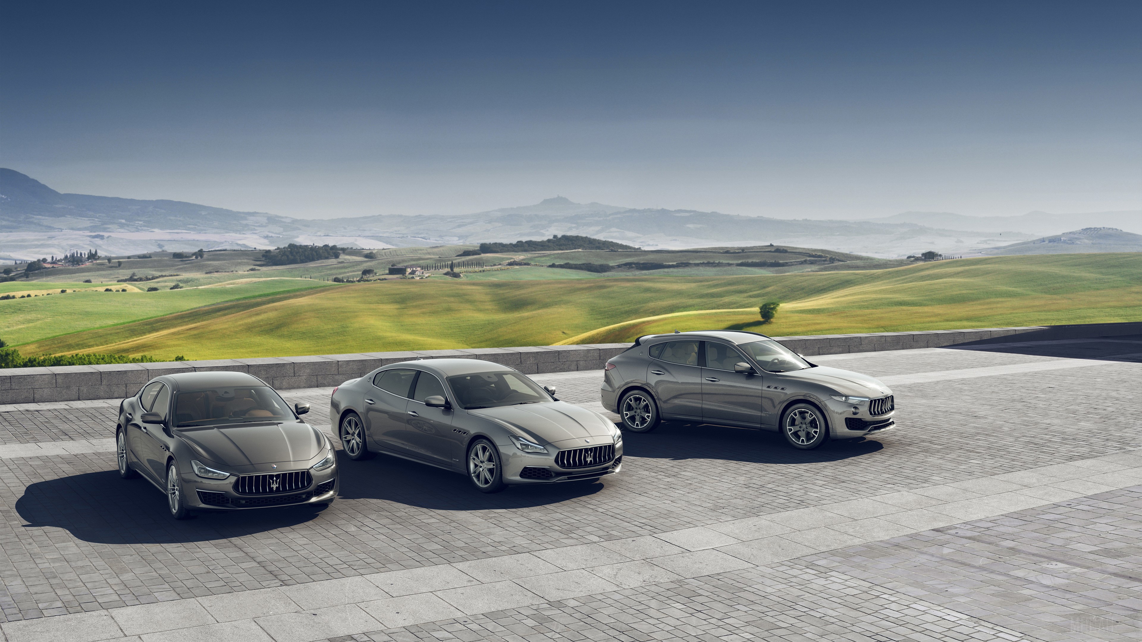 Three Maseratis parked in front of rolling hills HD Wallpaper