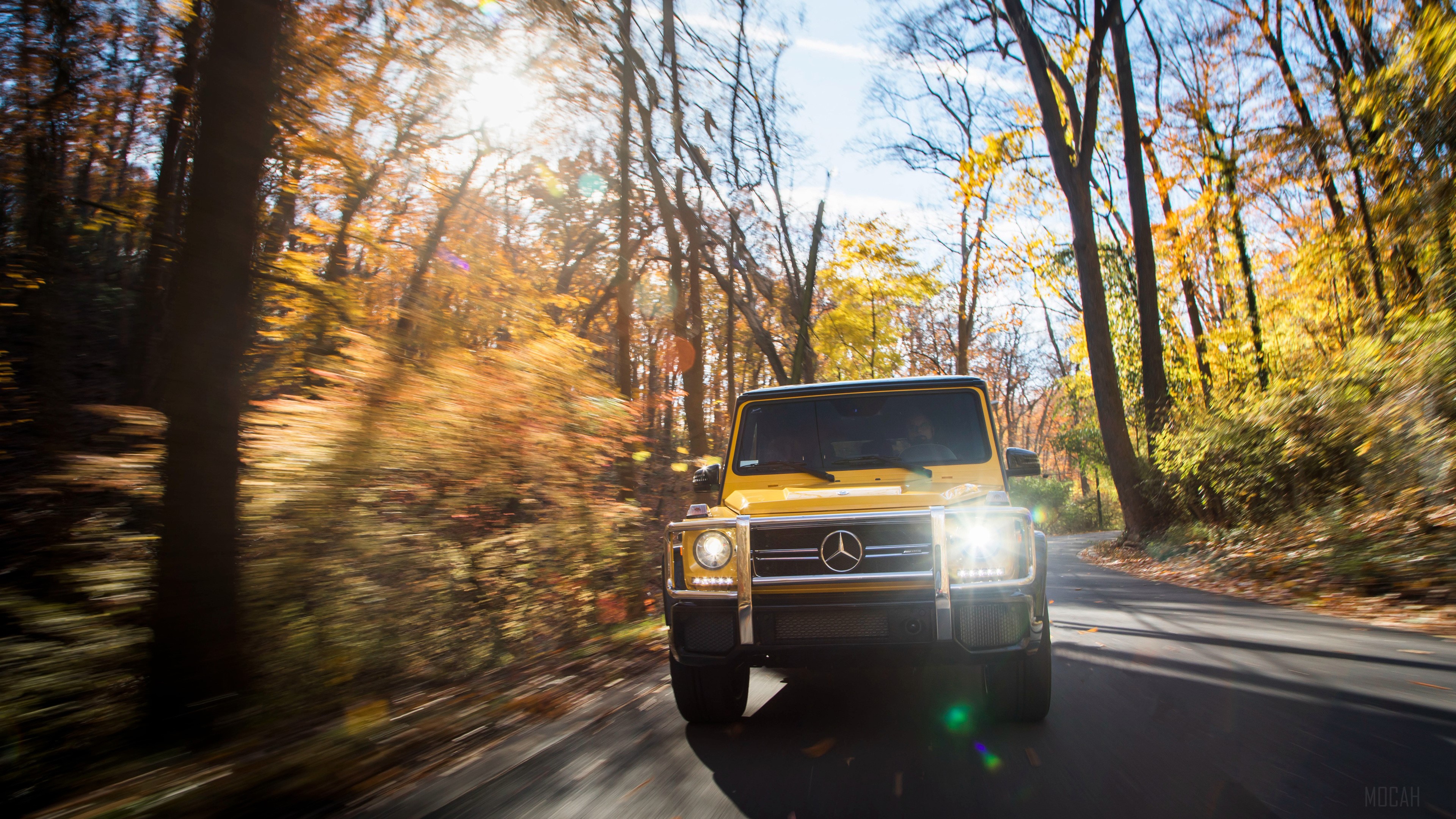 Yellow 2017 Mercedes AMG G63 driving on a road HD Wallpaper