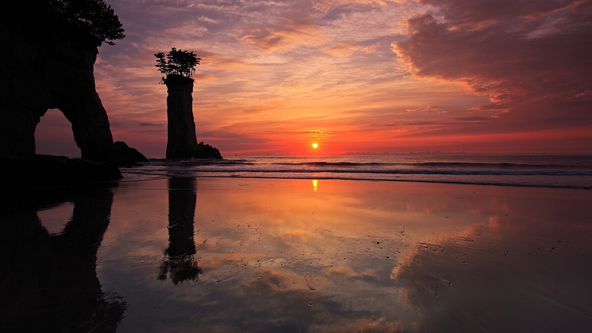 Sunset over the ocean with rock formations on a beach HD Wallpaper