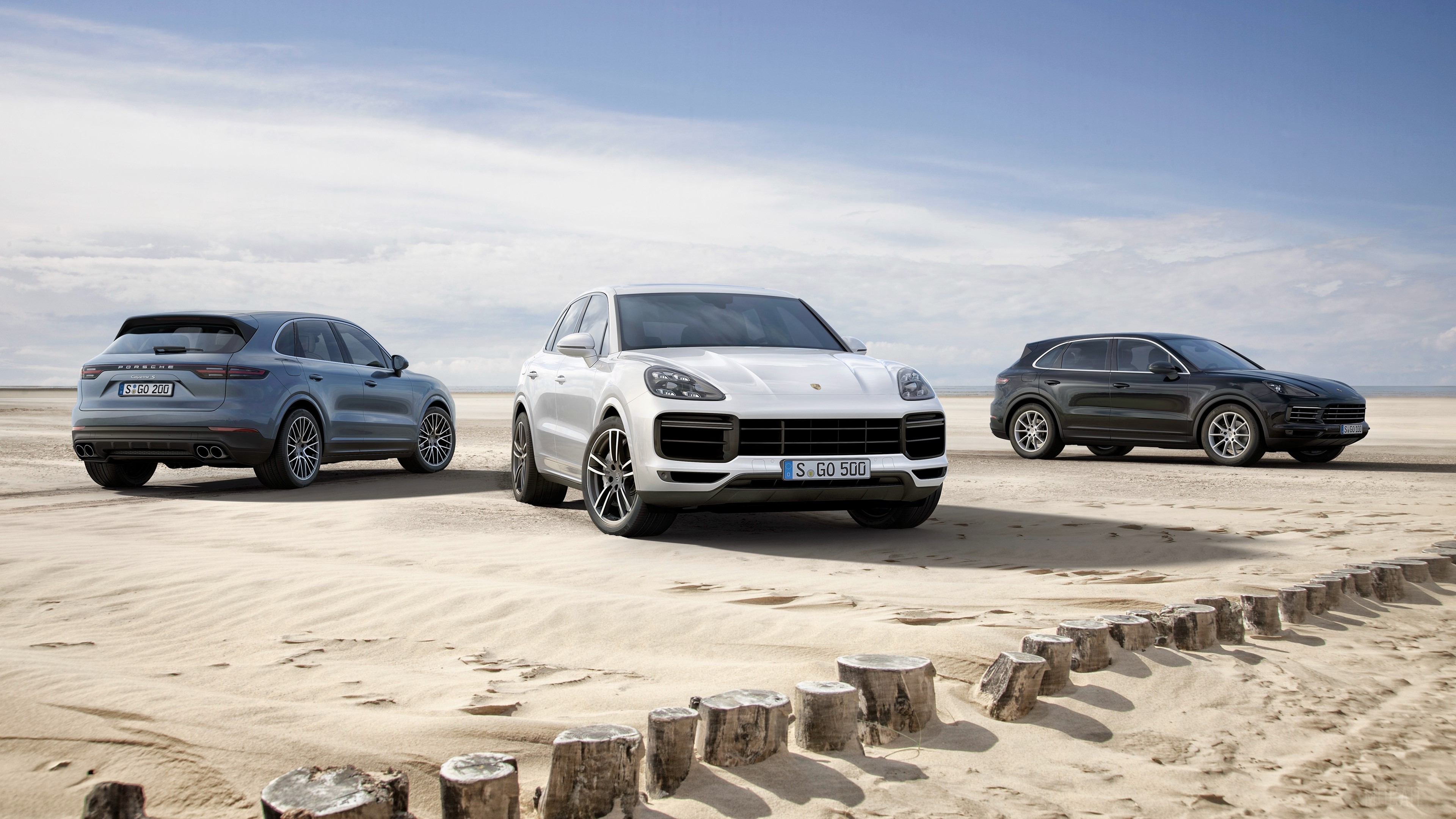 Three Porsche Cayenne SUVs on a Sandy Beach HD Wallpaper