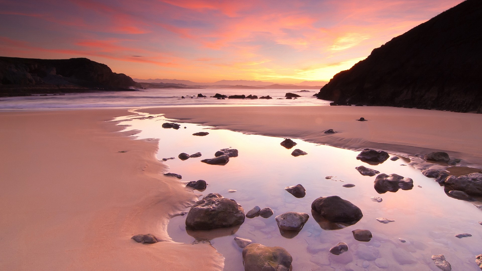 Beach at sunset with calm water and rocks HD Wallpaper