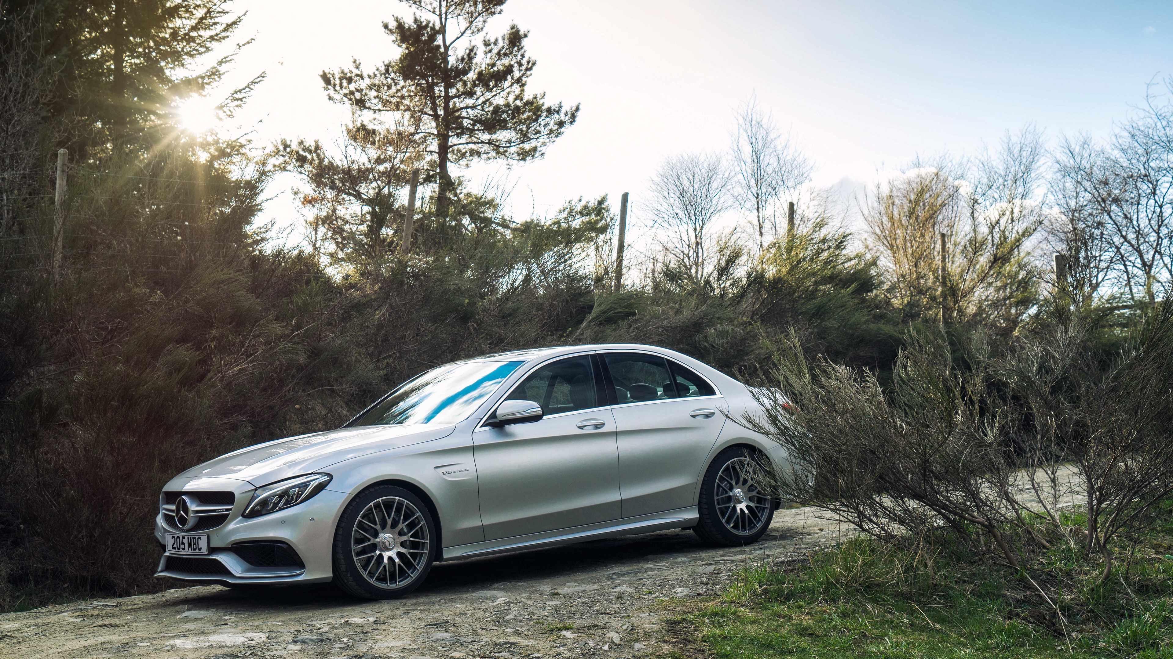 Silver Mercedes-AMG C 63 S sedan on a dirt road HD Wallpaper
