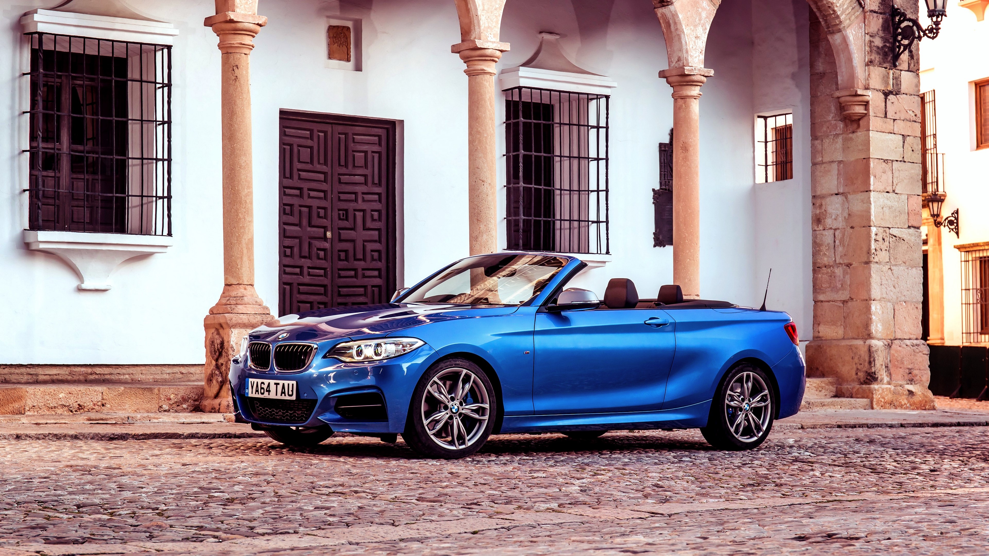 Blue BMW M235i Convertible parked on cobblestone street HD Wallpaper