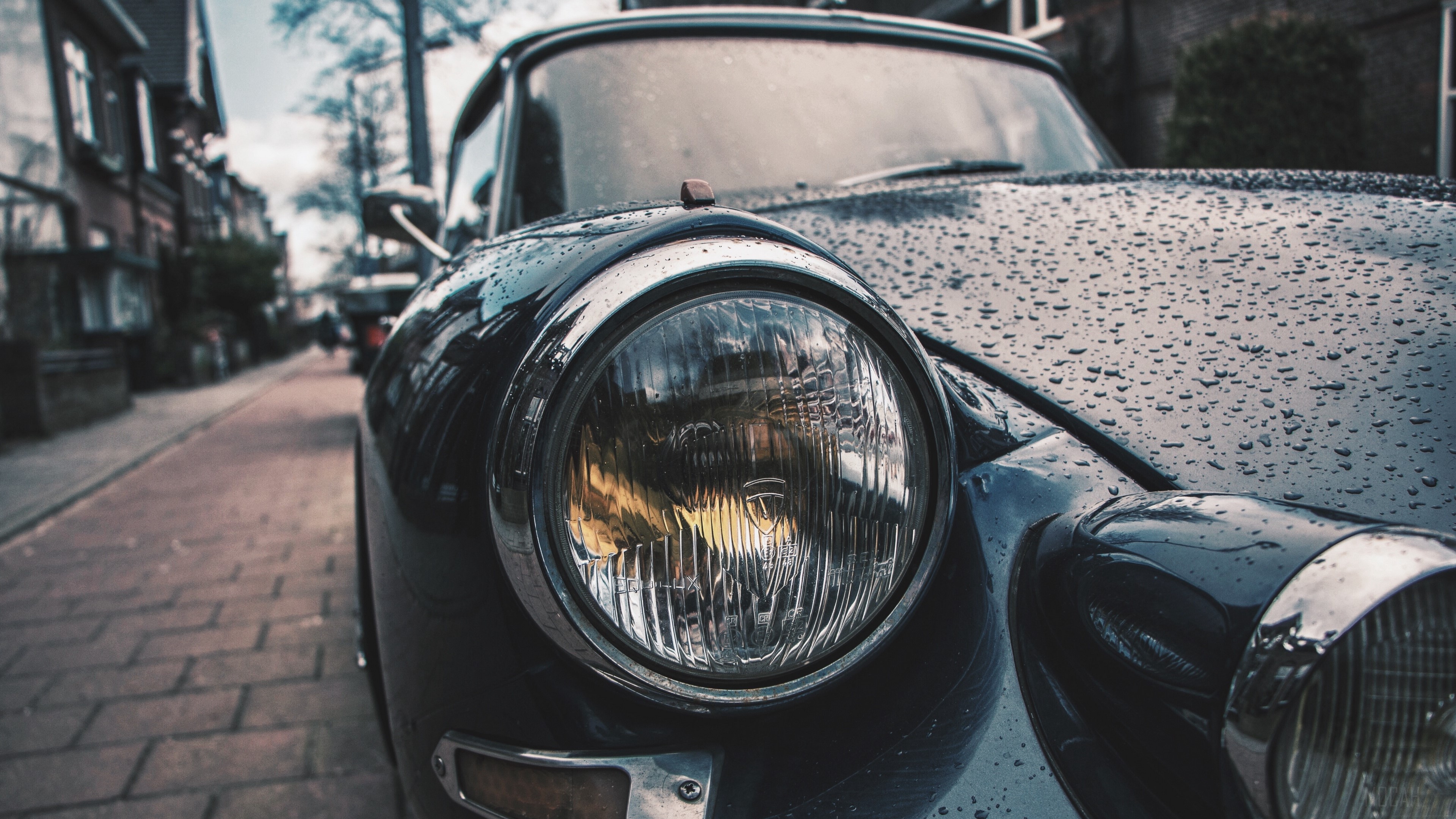 Close-up of a vintage car headlight with raindrops HD Wallpaper