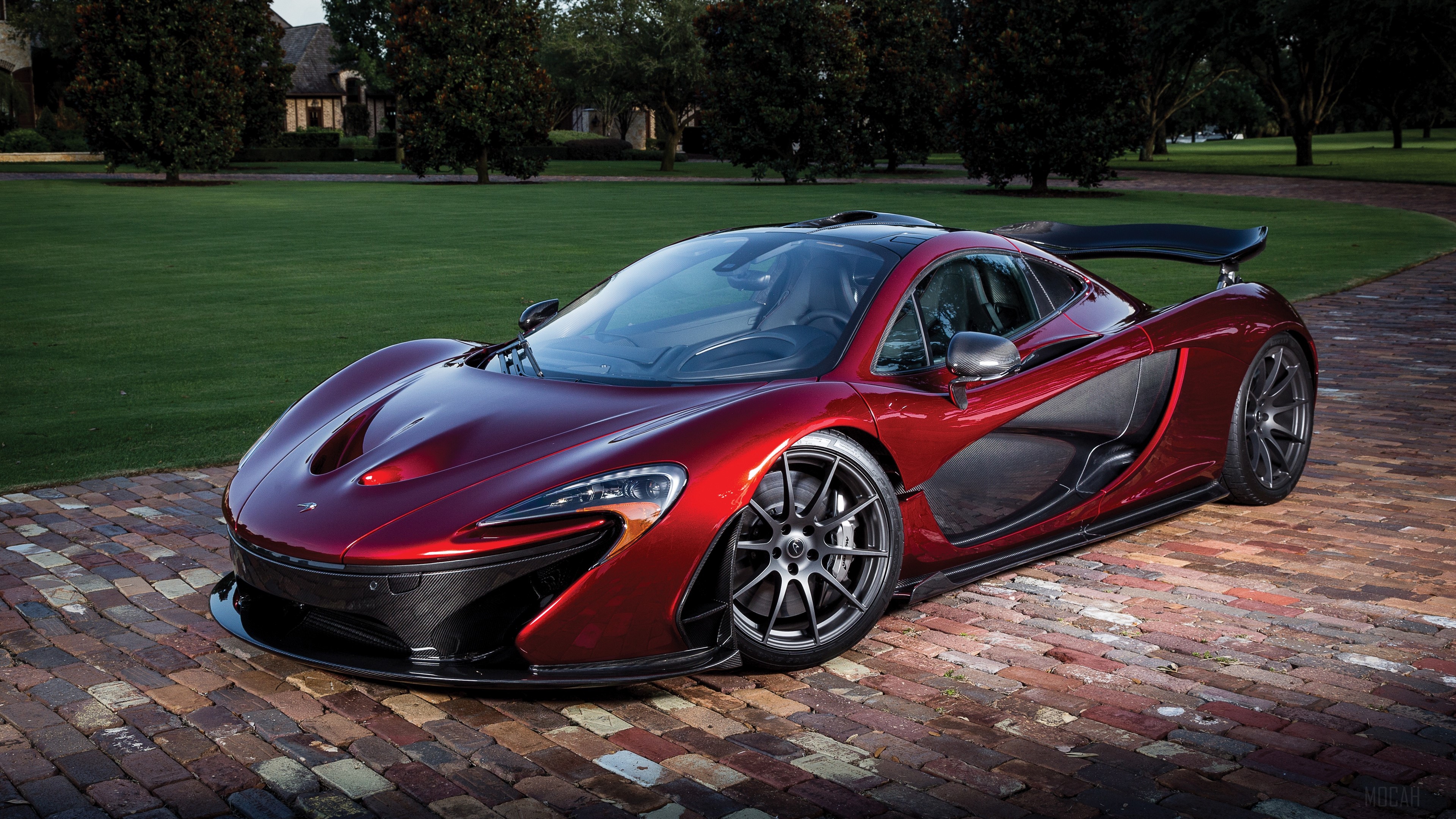 Red McLaren P1 sports car on a brick driveway HD Wallpaper
