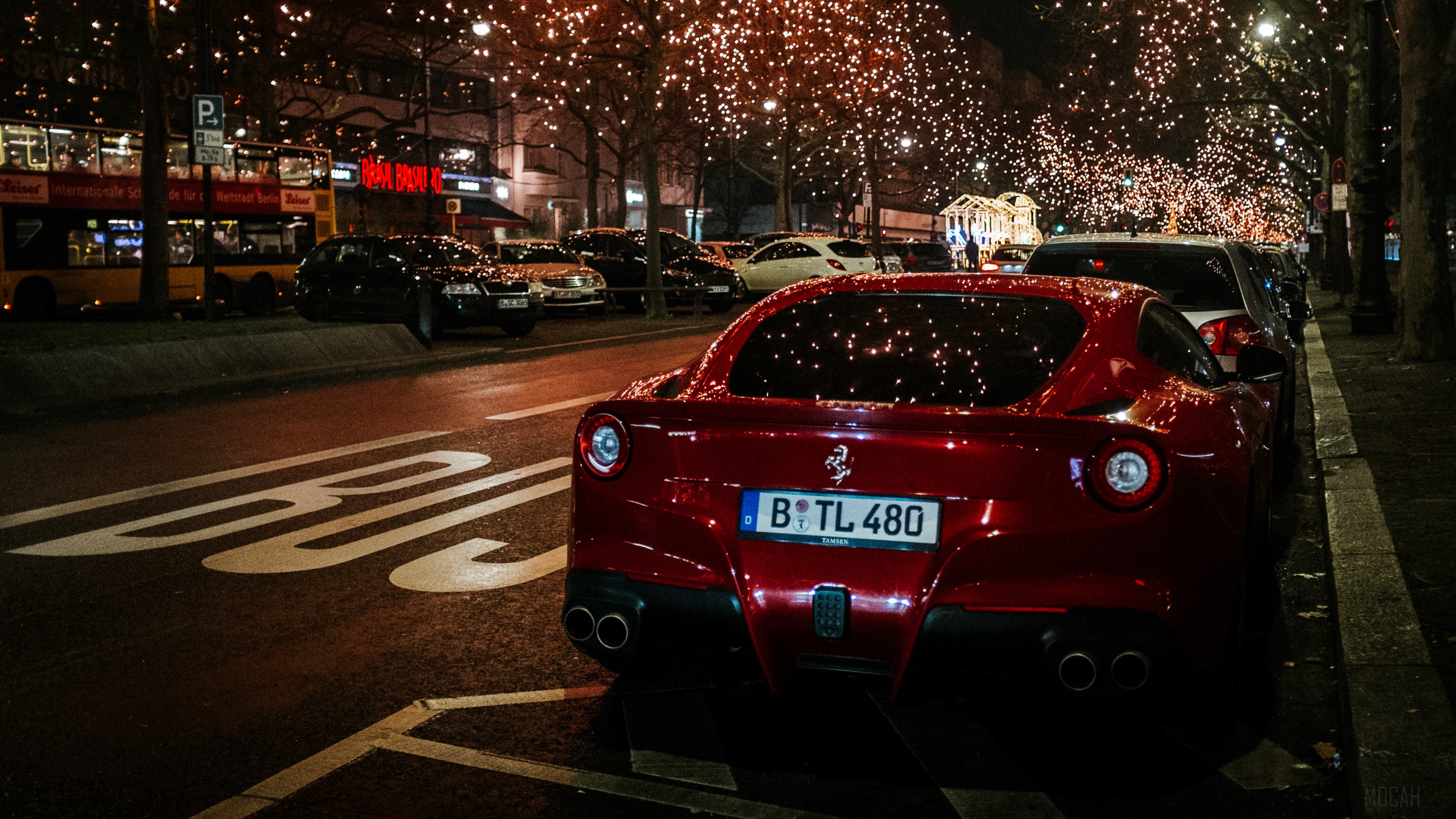 Red Ferrari F12 Berlinetta parked at night with city lights HD Wallpaper