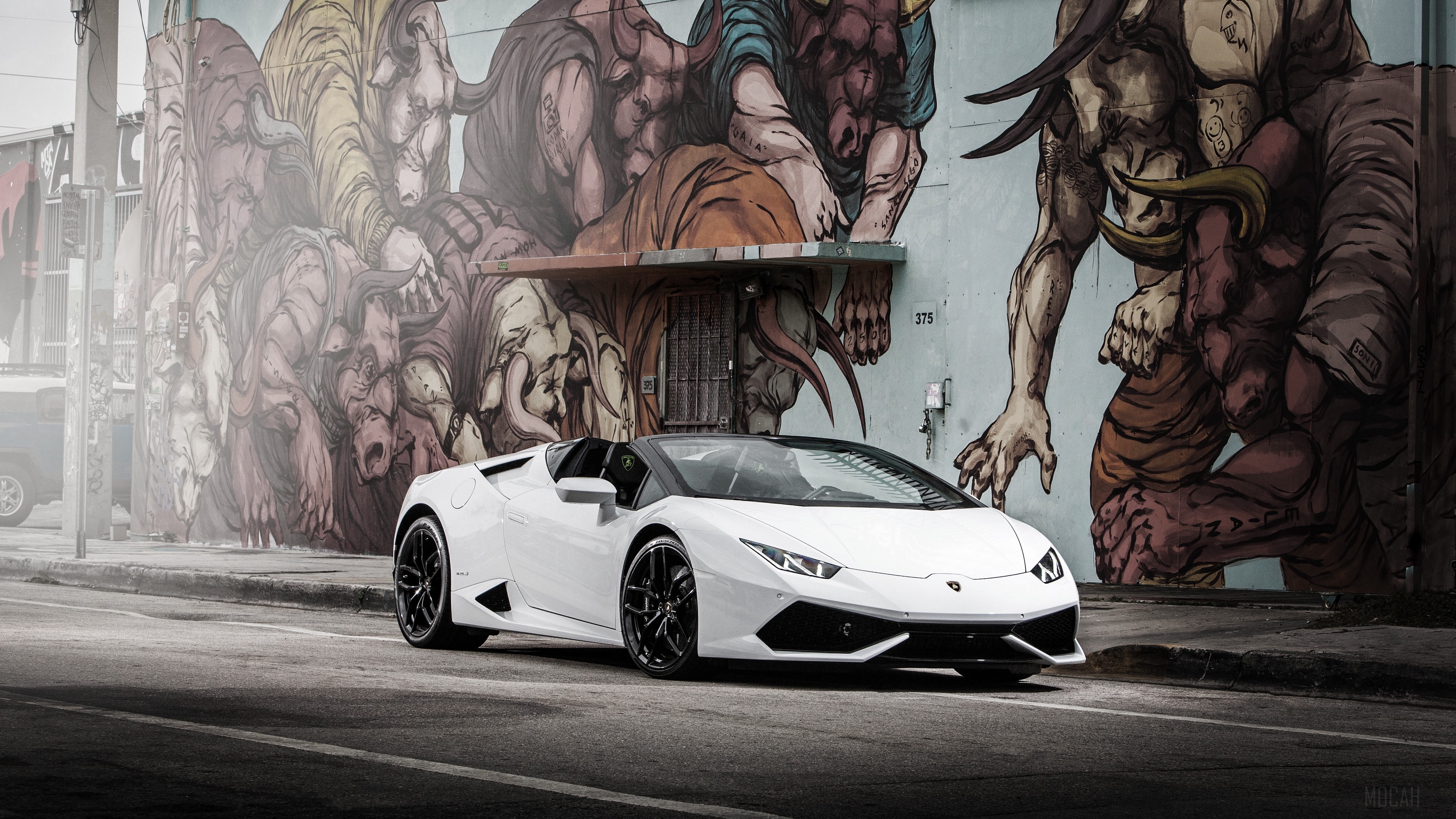 White Lamborghini Huracan parked in front of a mural HD Wallpaper