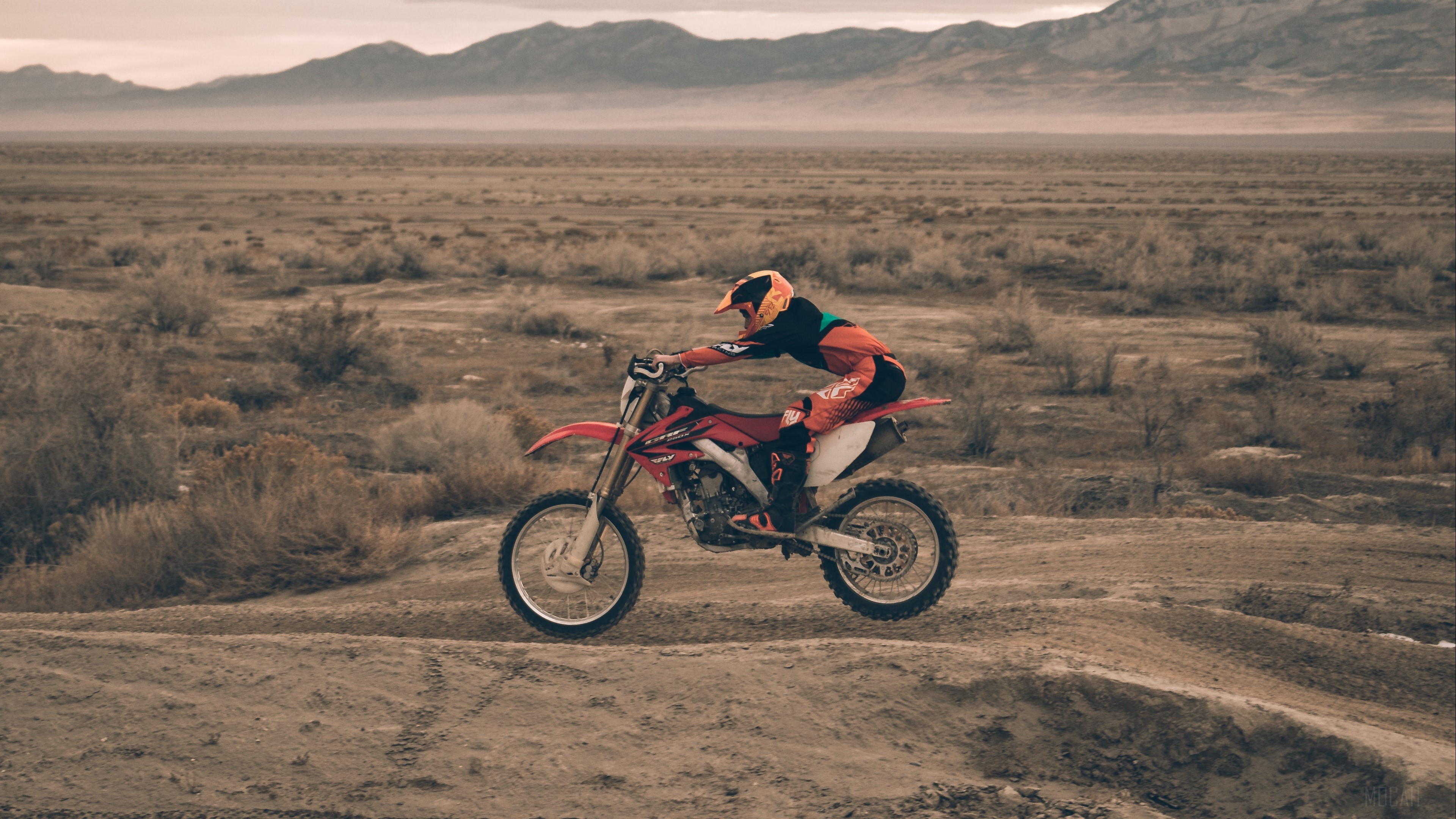 Motocross rider jumping in a desert landscape HD Wallpaper