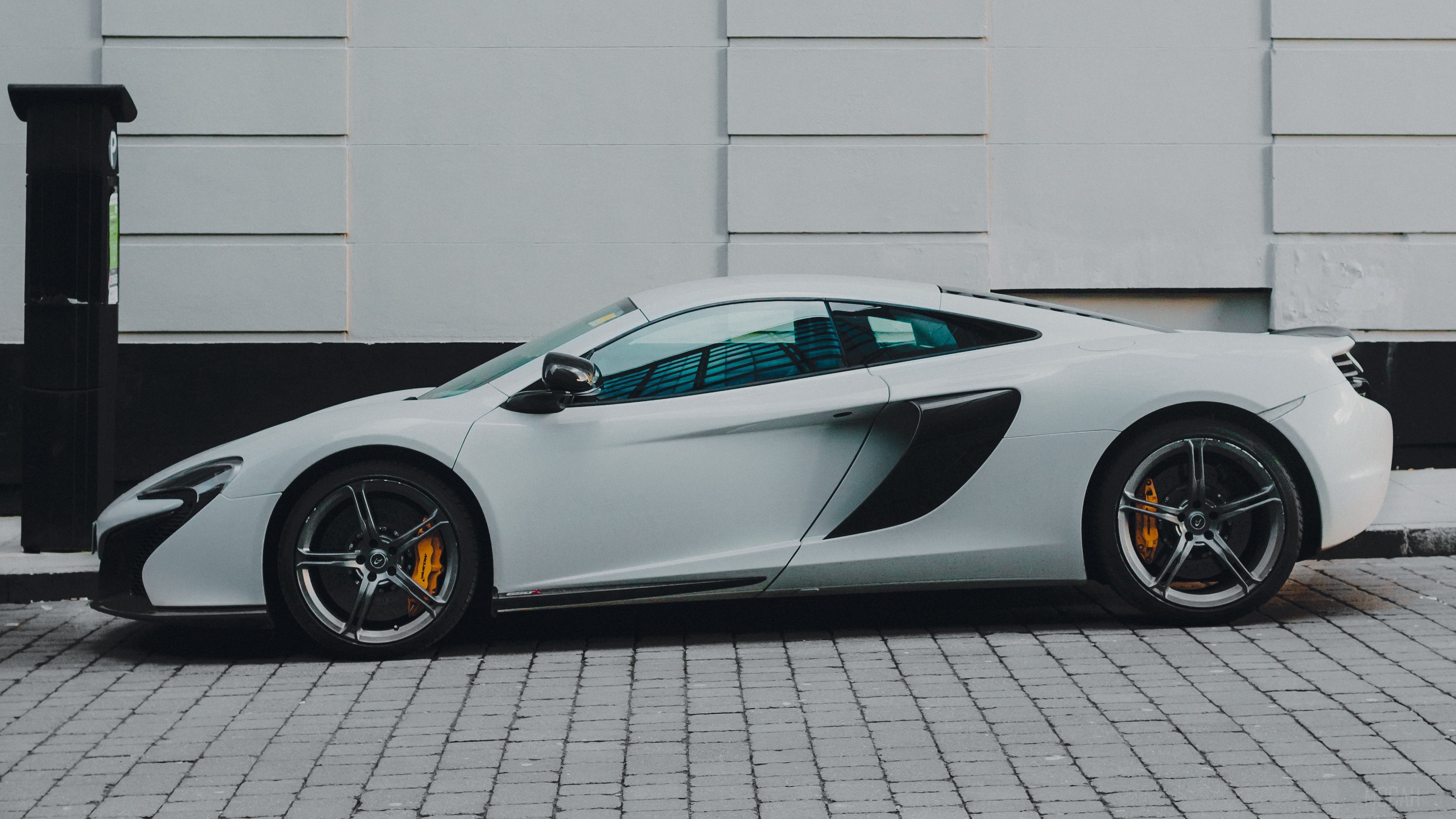 White McLaren sports car parked on a cobblestone street HD Wallpaper