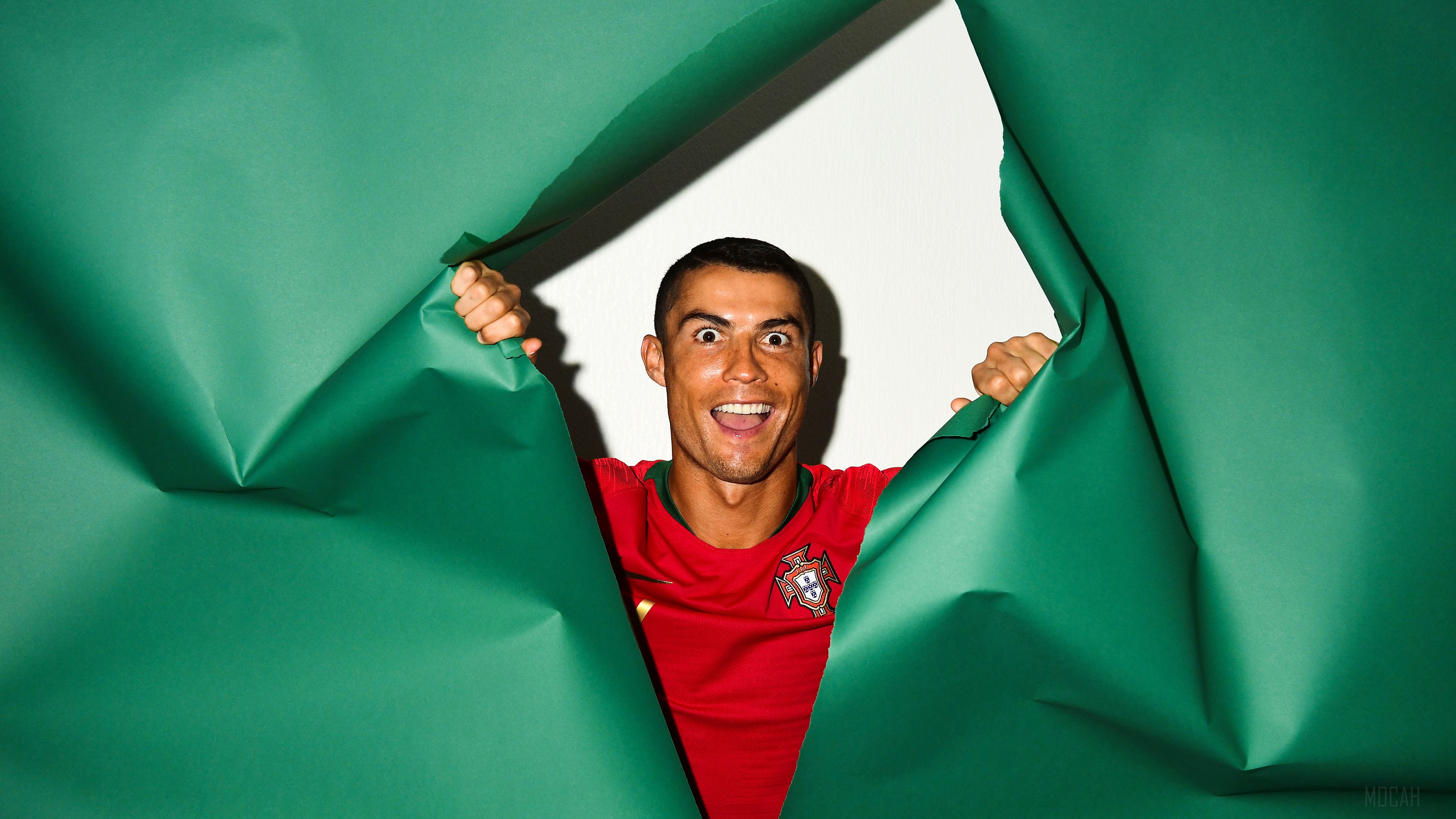 Cristiano Ronaldo of Portugal peeking through green paper HD Wallpaper