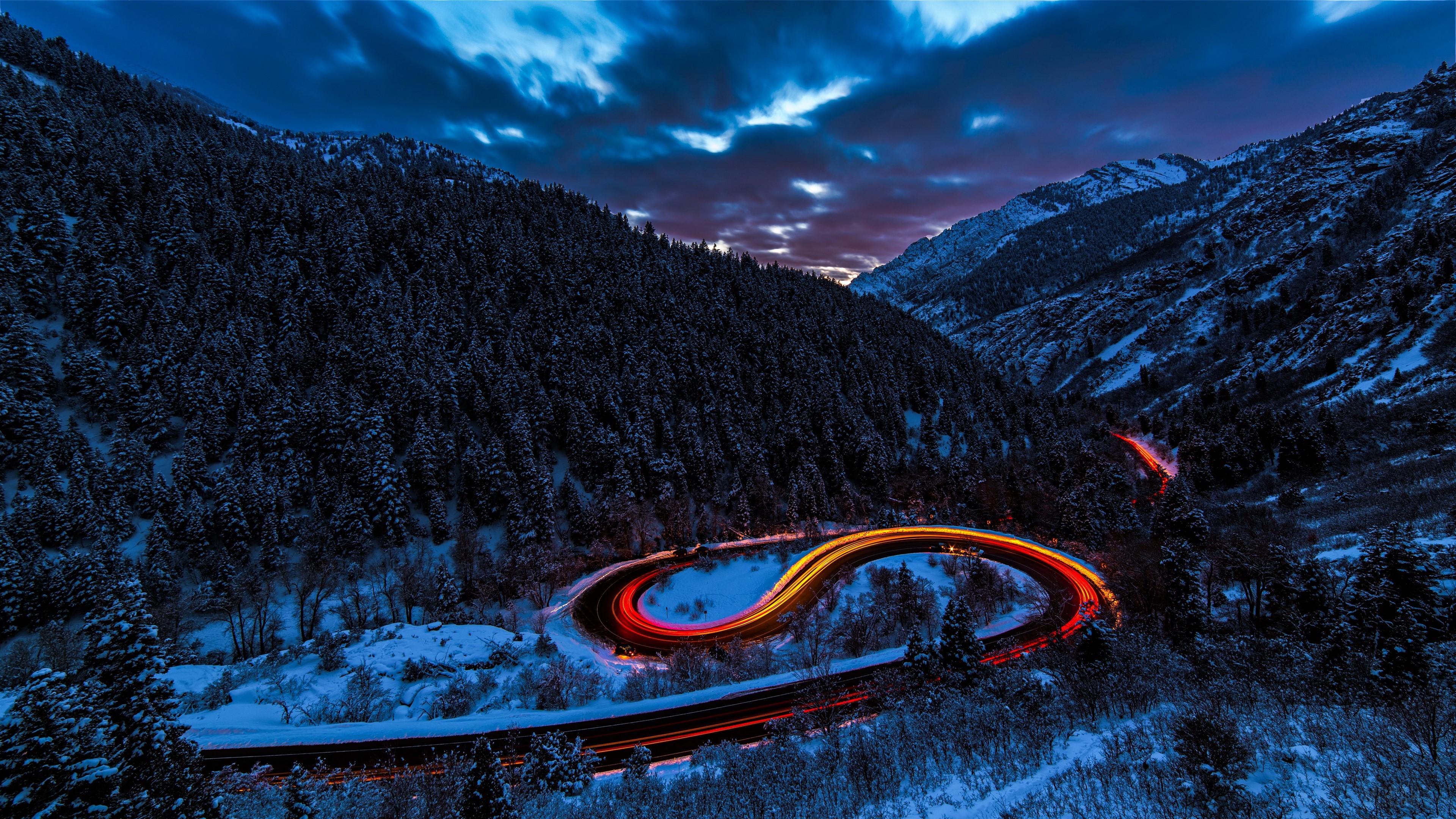 Winding mountain road with light trails in snow 4K HD Wallpaper