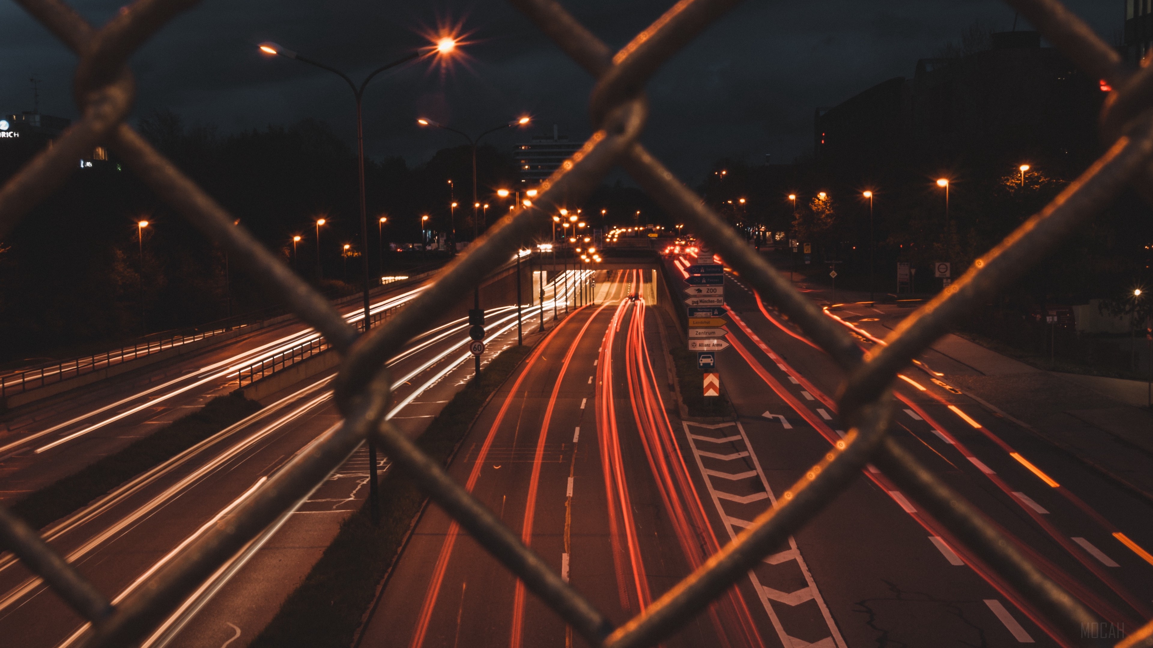 Night road with light trails behind a fence HD Wallpaper