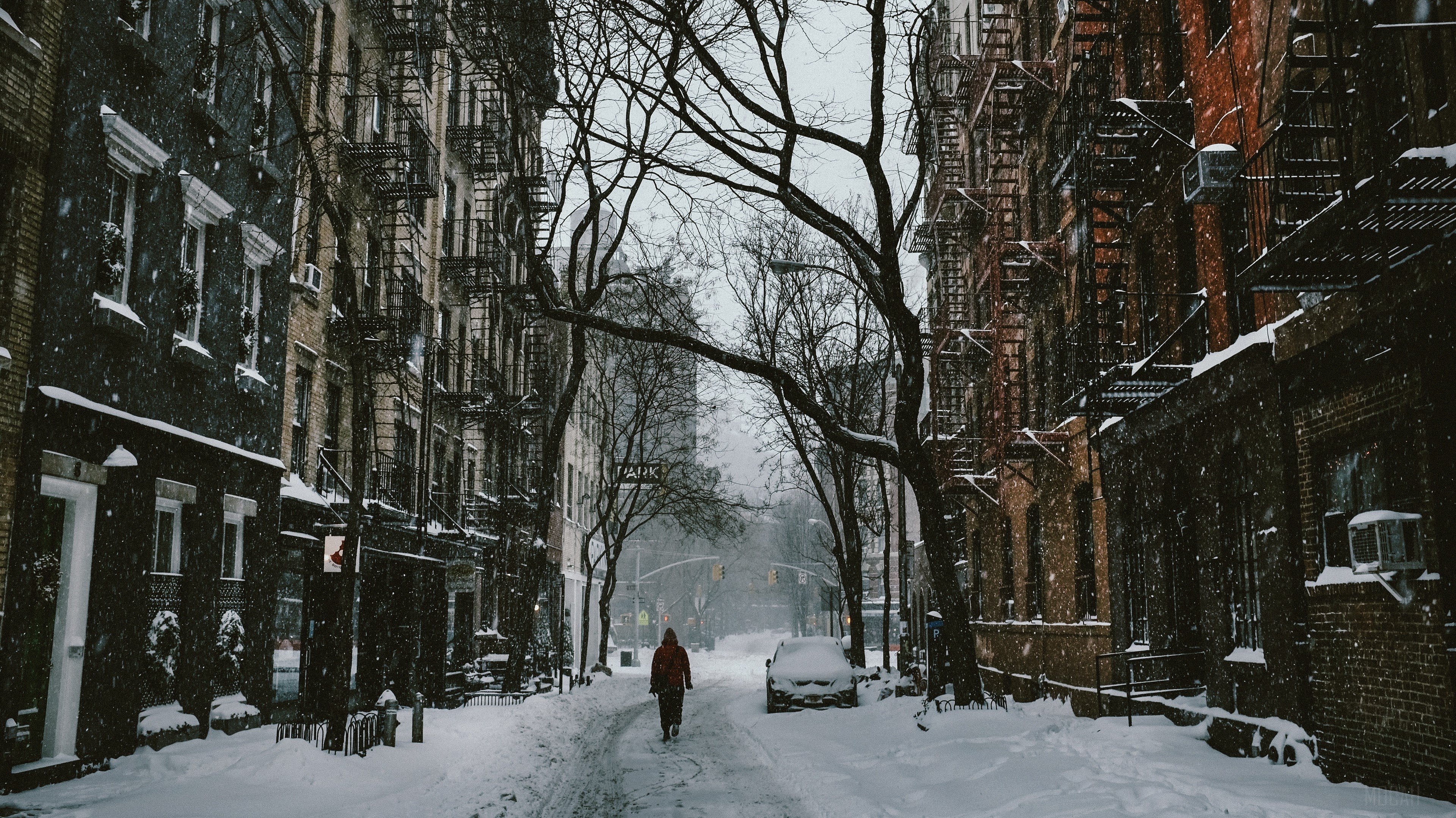 Person walking down a snowy city street in winter HD Wallpaper