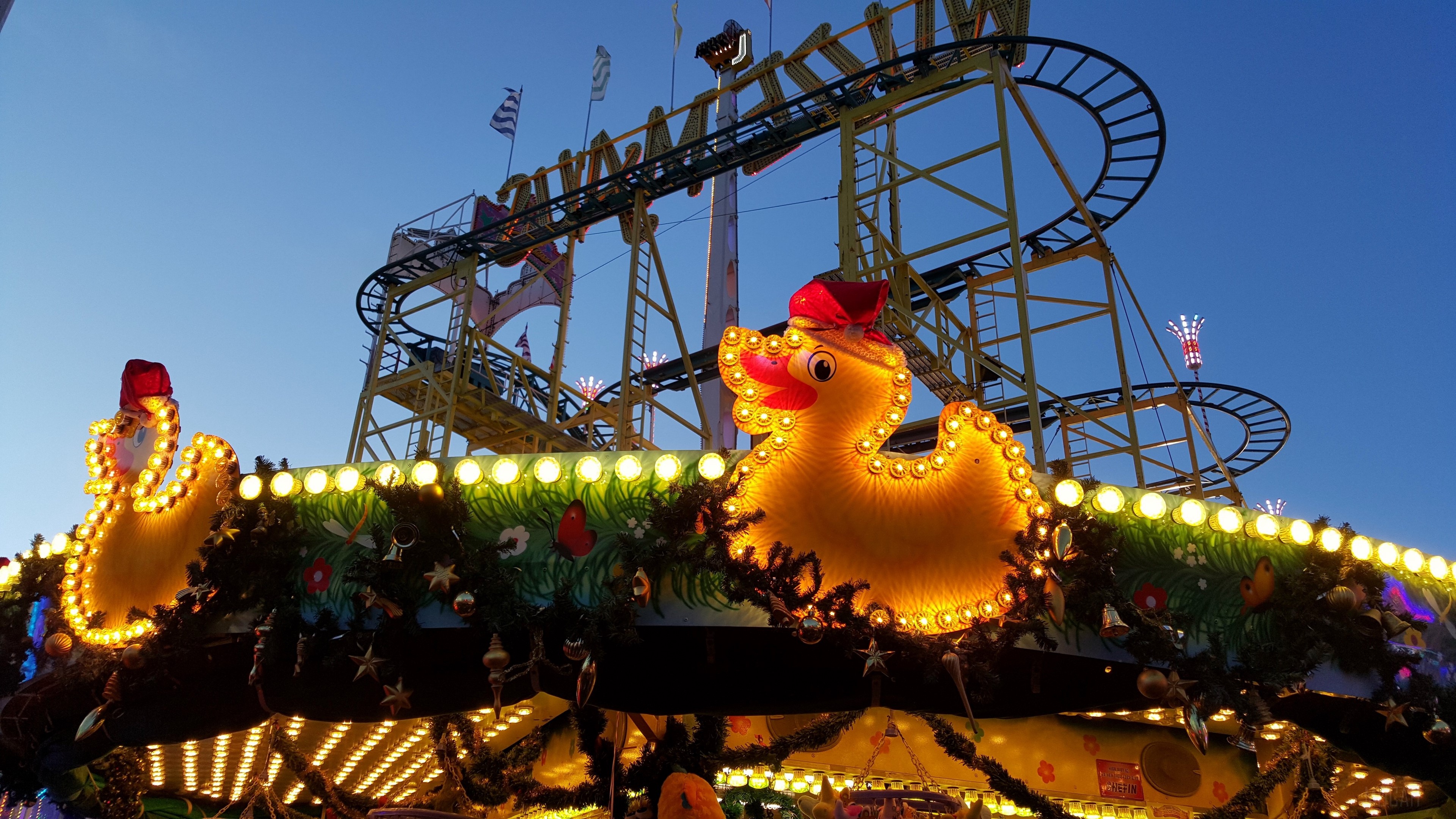 Roller coaster with illuminated duck decorations at dusk HD Wallpaper