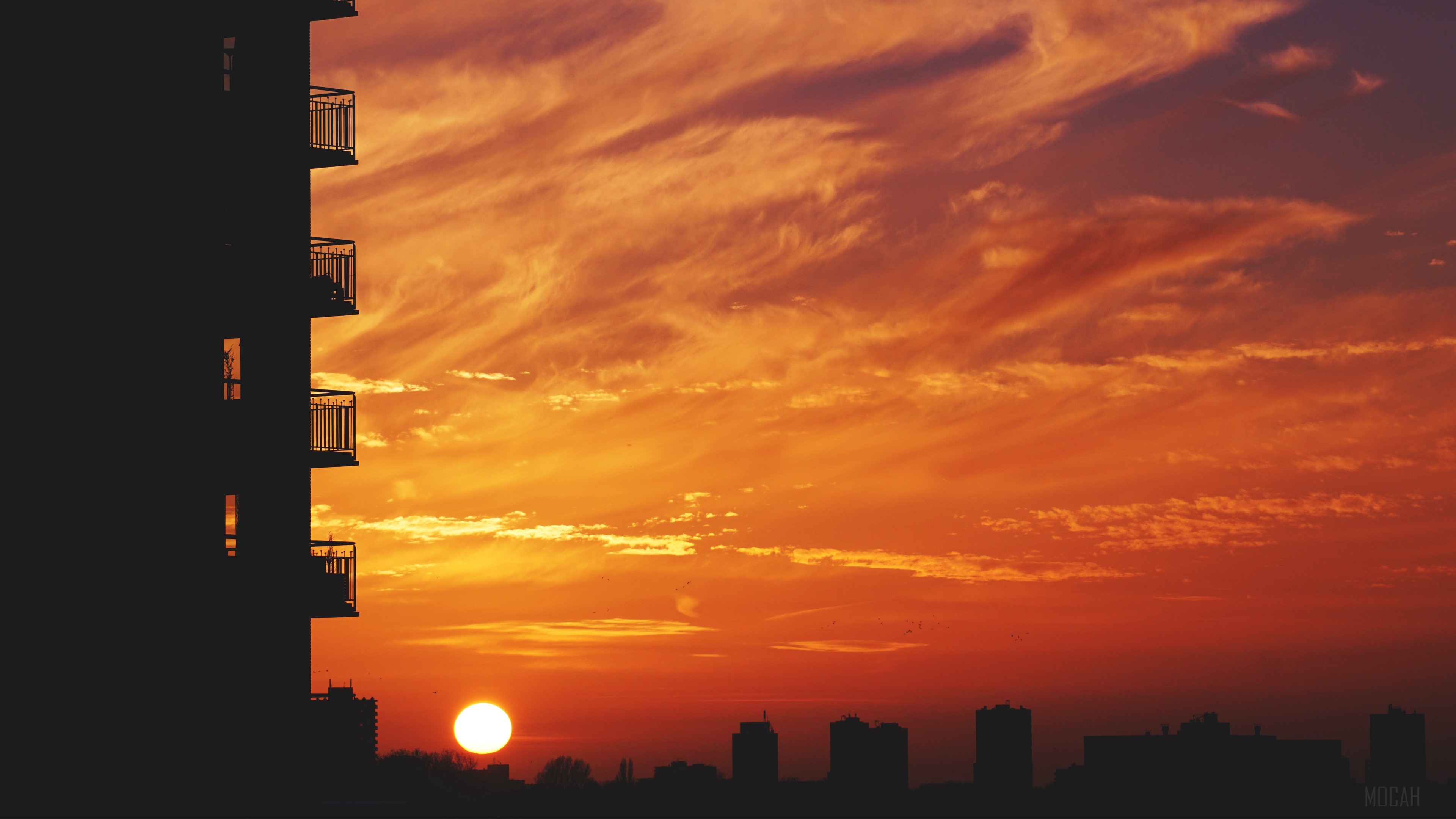 Sunset over city skyline with building balconies HD Wallpaper