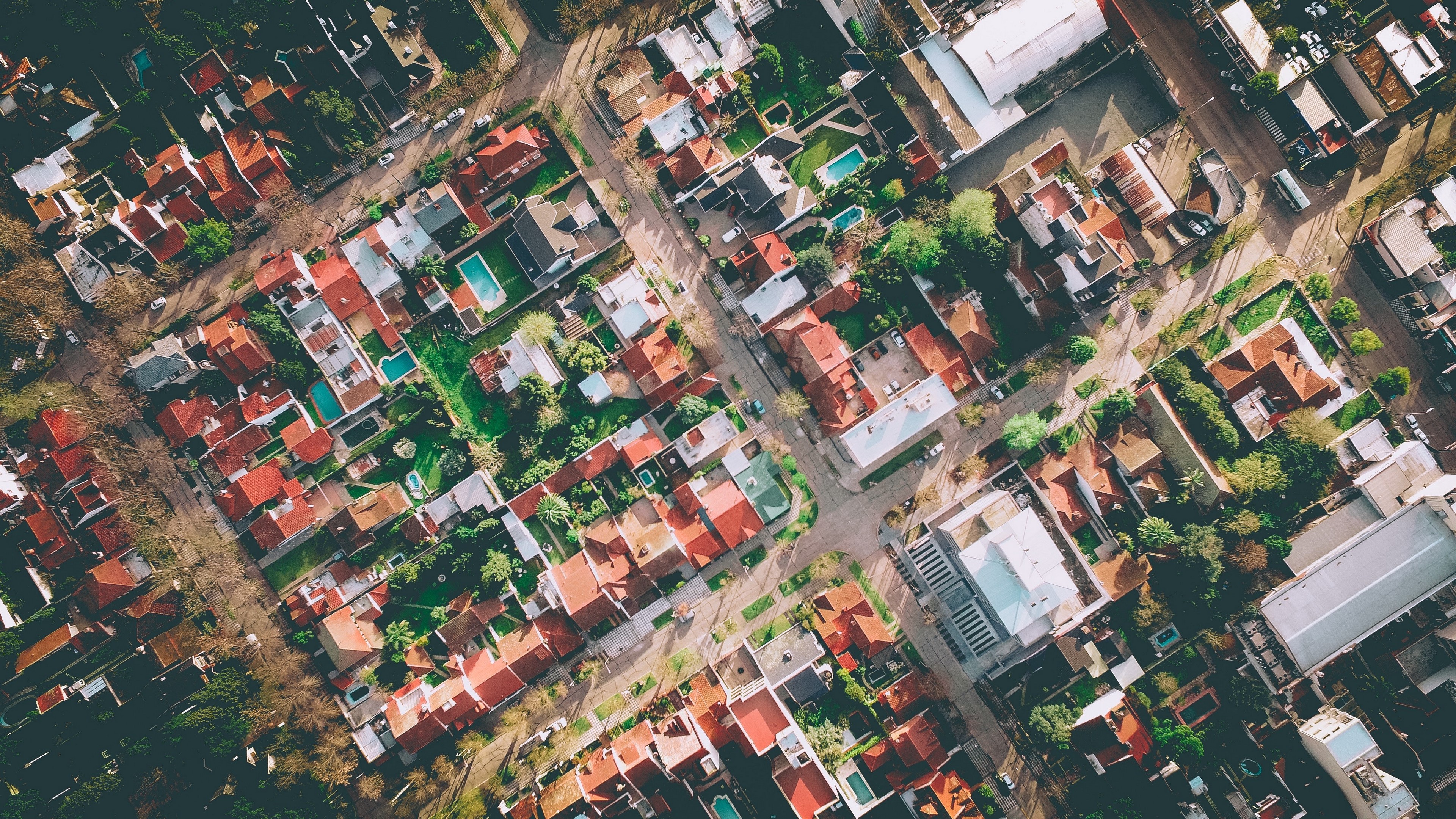 Aerial view of a residential neighborhood with red-tiled roofs HD Wallpaper