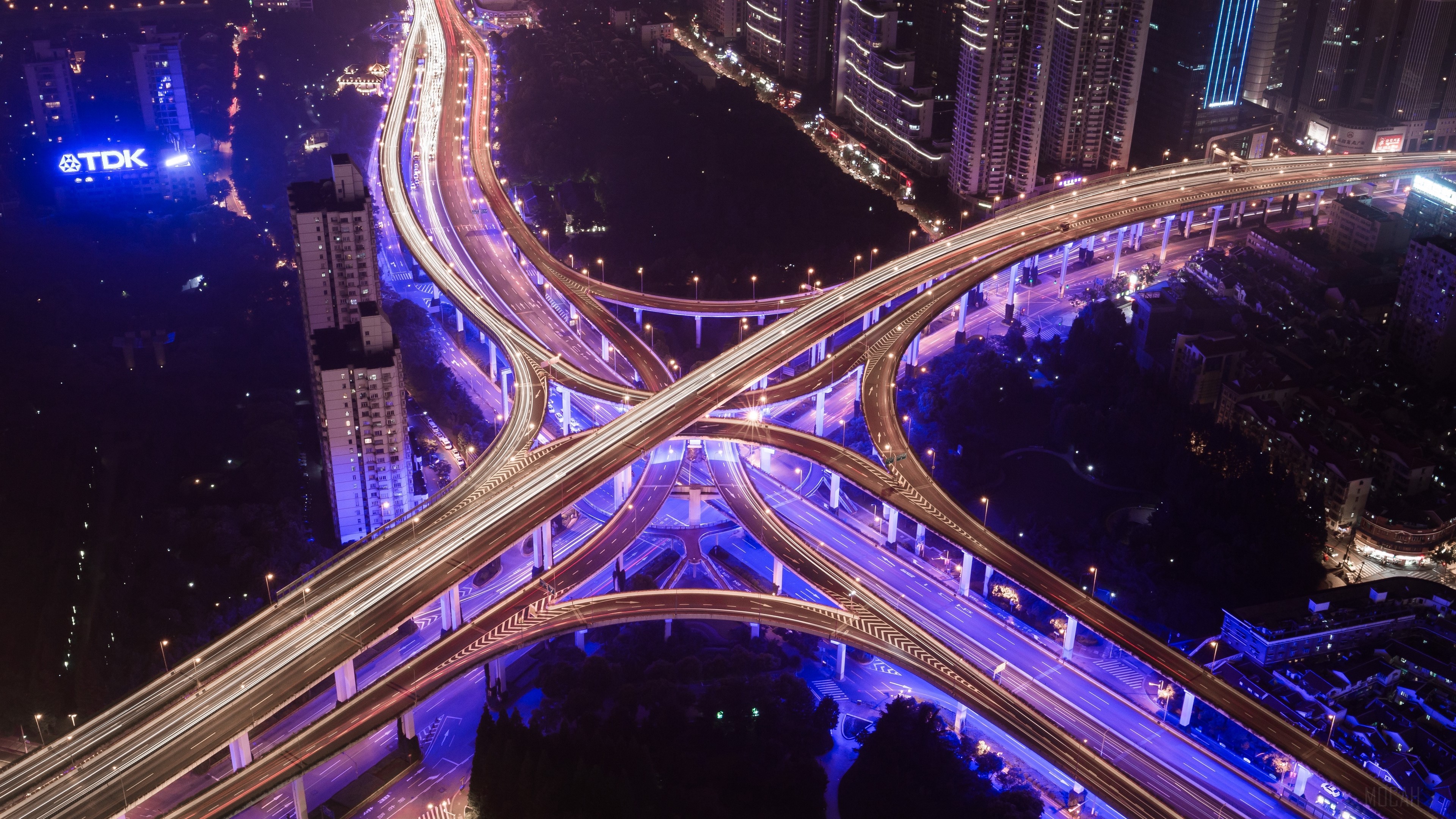 Aerial view of a brightly lit city highway interchange at night HD Wallpaper