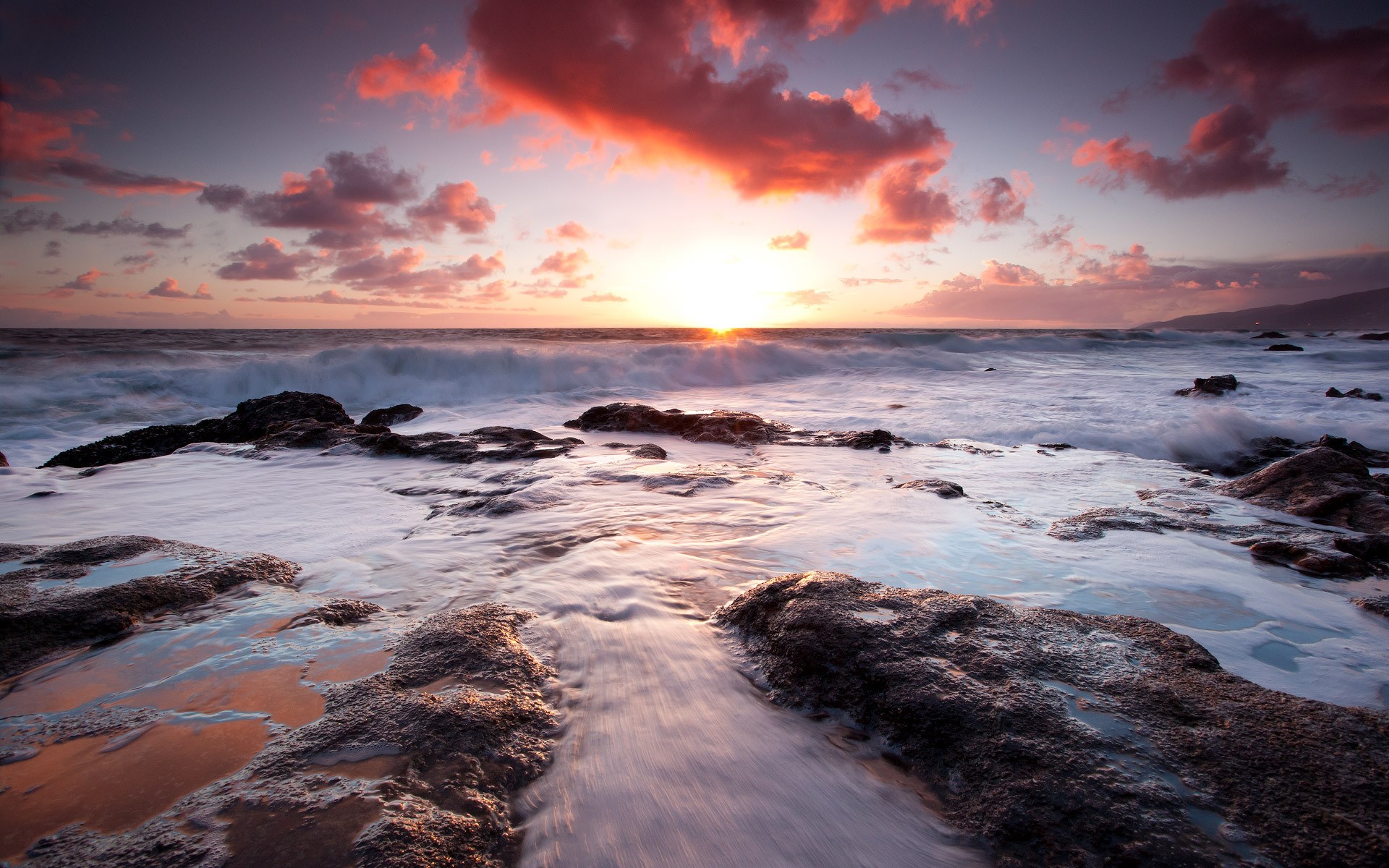 Ocean waves crashing on rocky shore at sunset HD Wallpaper
