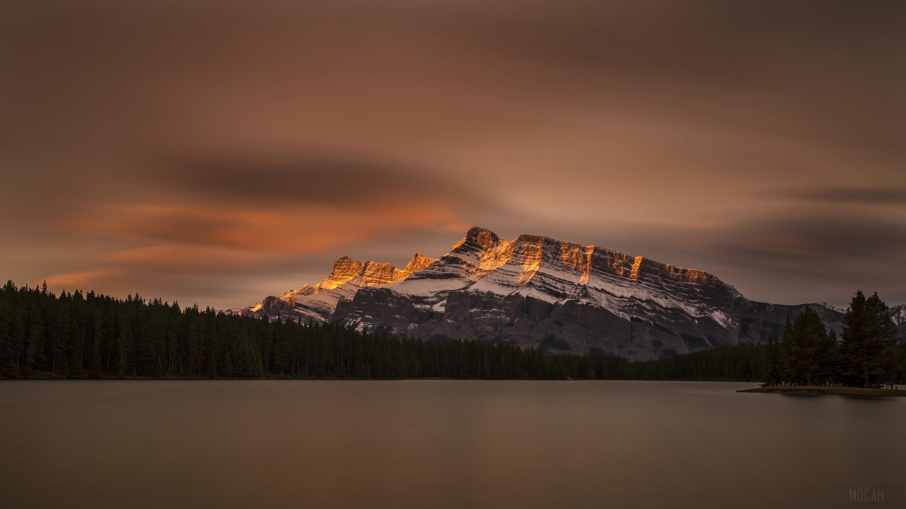 Mountaintop illuminated by sunset over a lake in Banff National Park 4K HD Wallpaper