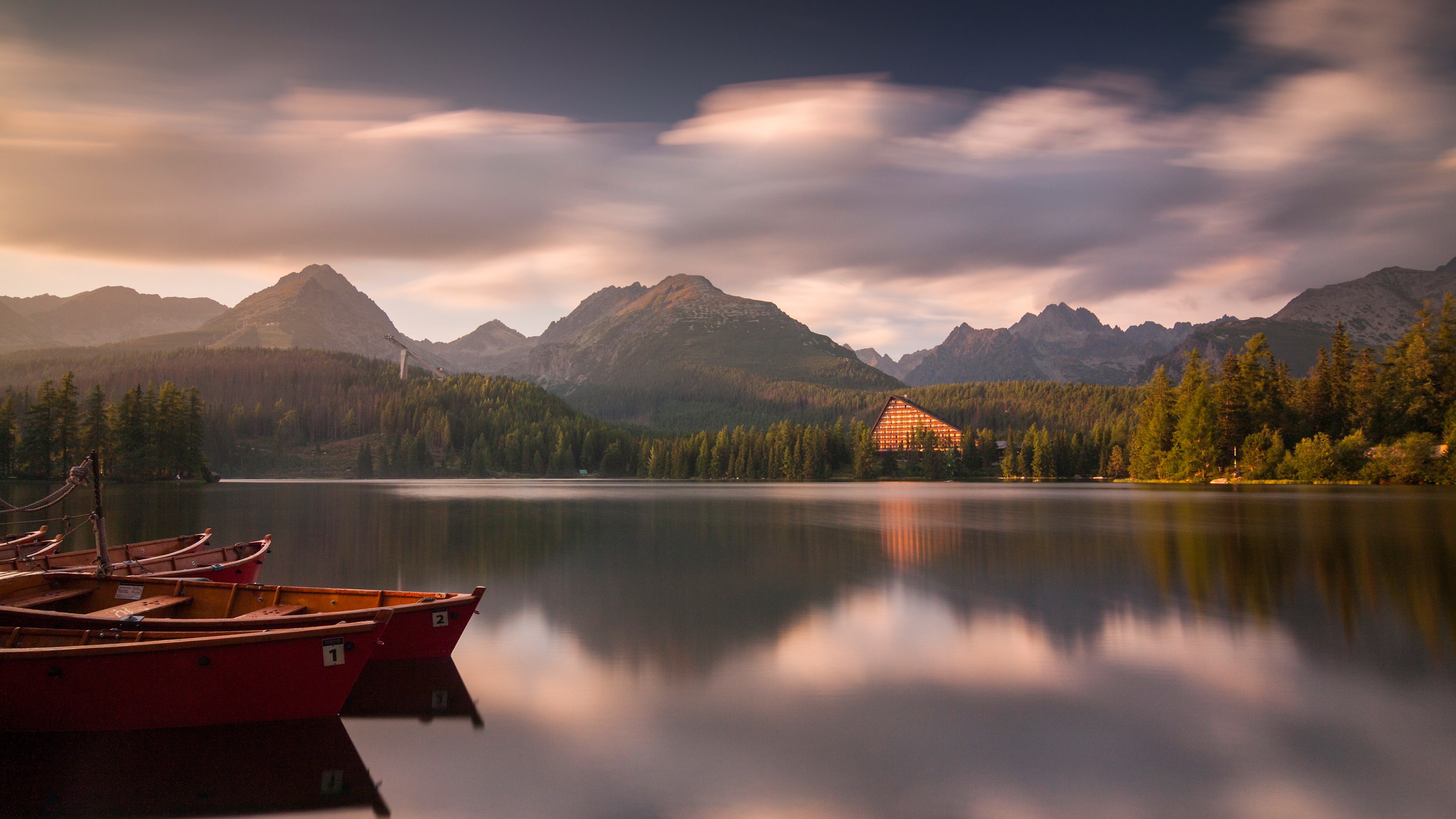 Boats on a lake with mountains and a building HD Wallpaper