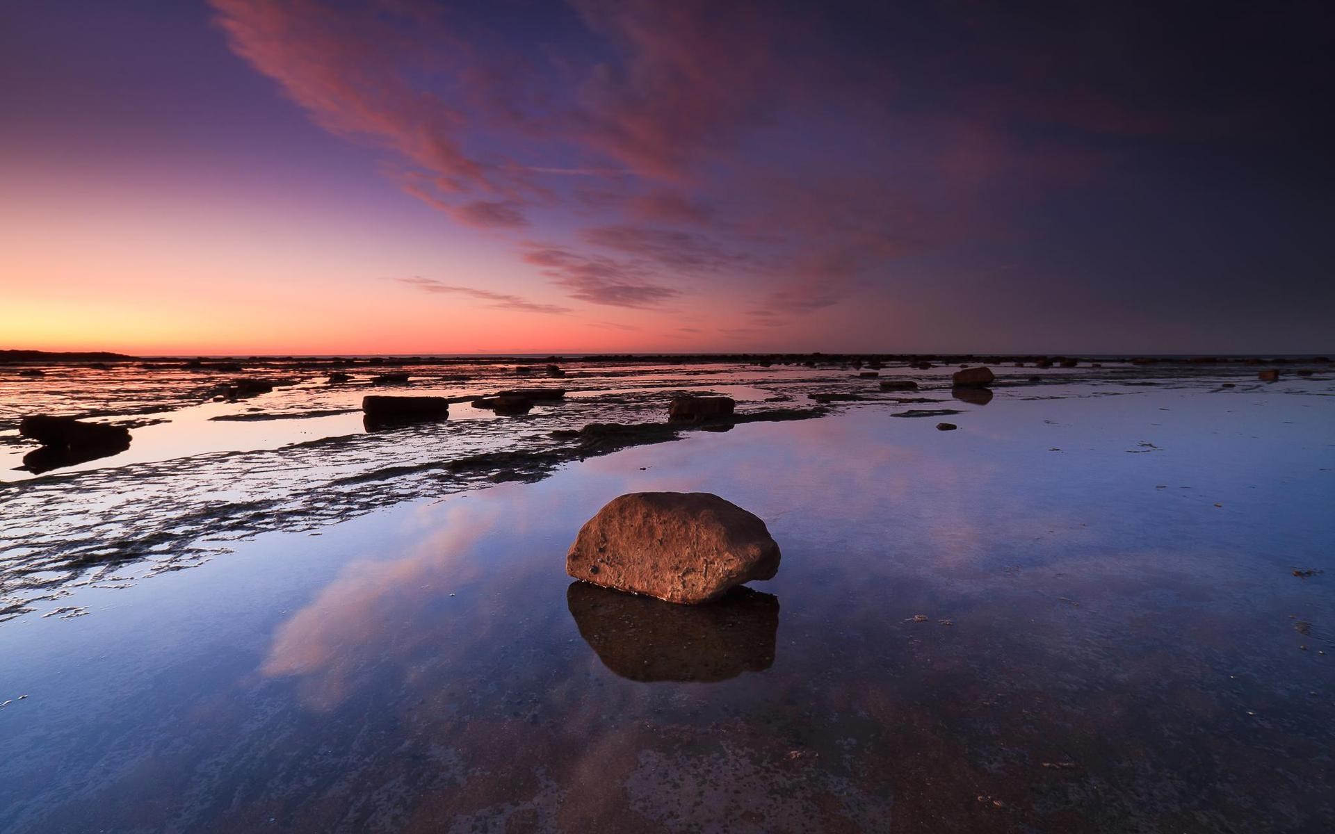 Rocky shore at sunset with colorful sky reflection HD Wallpaper