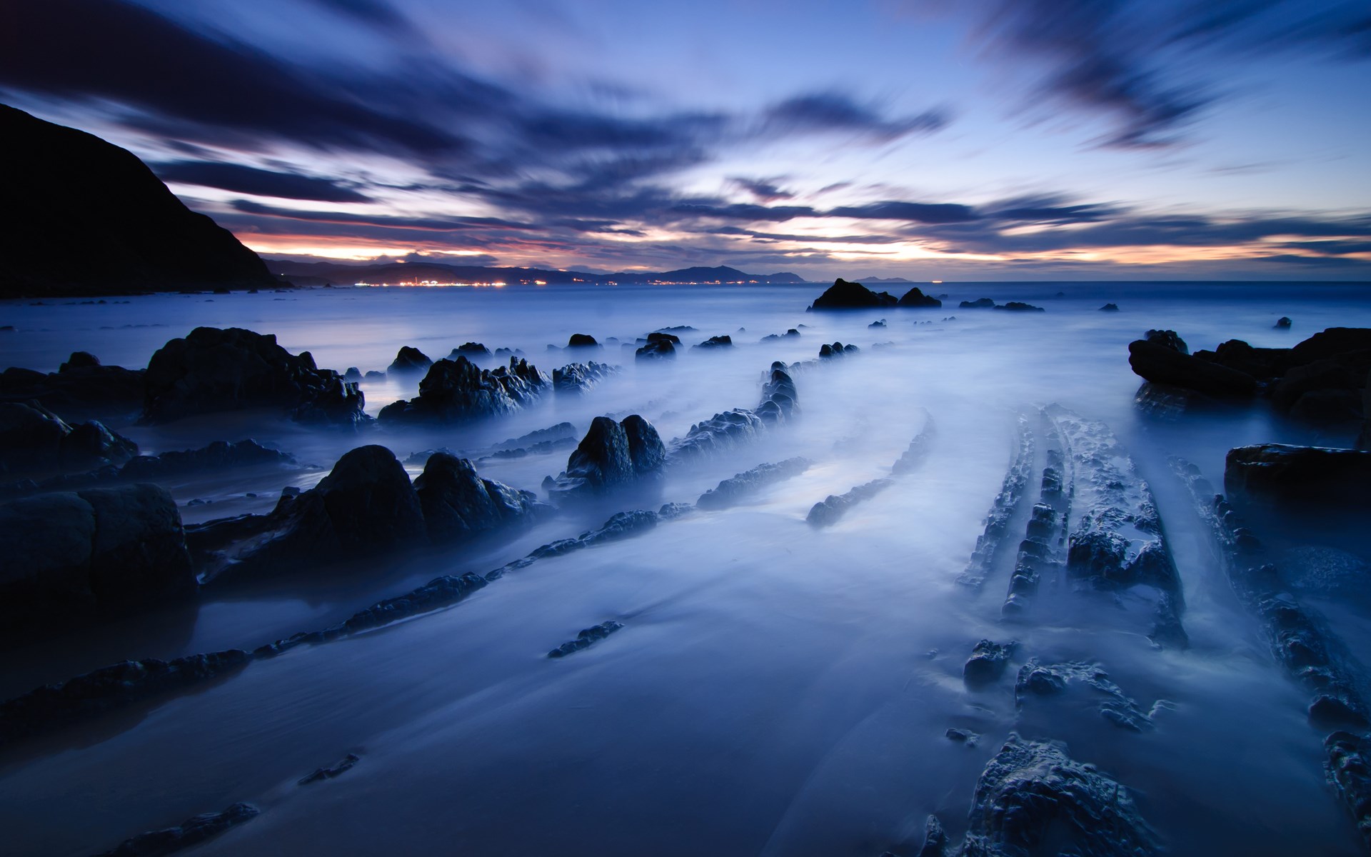 Rocky coastline at dusk with misty water HD Wallpaper