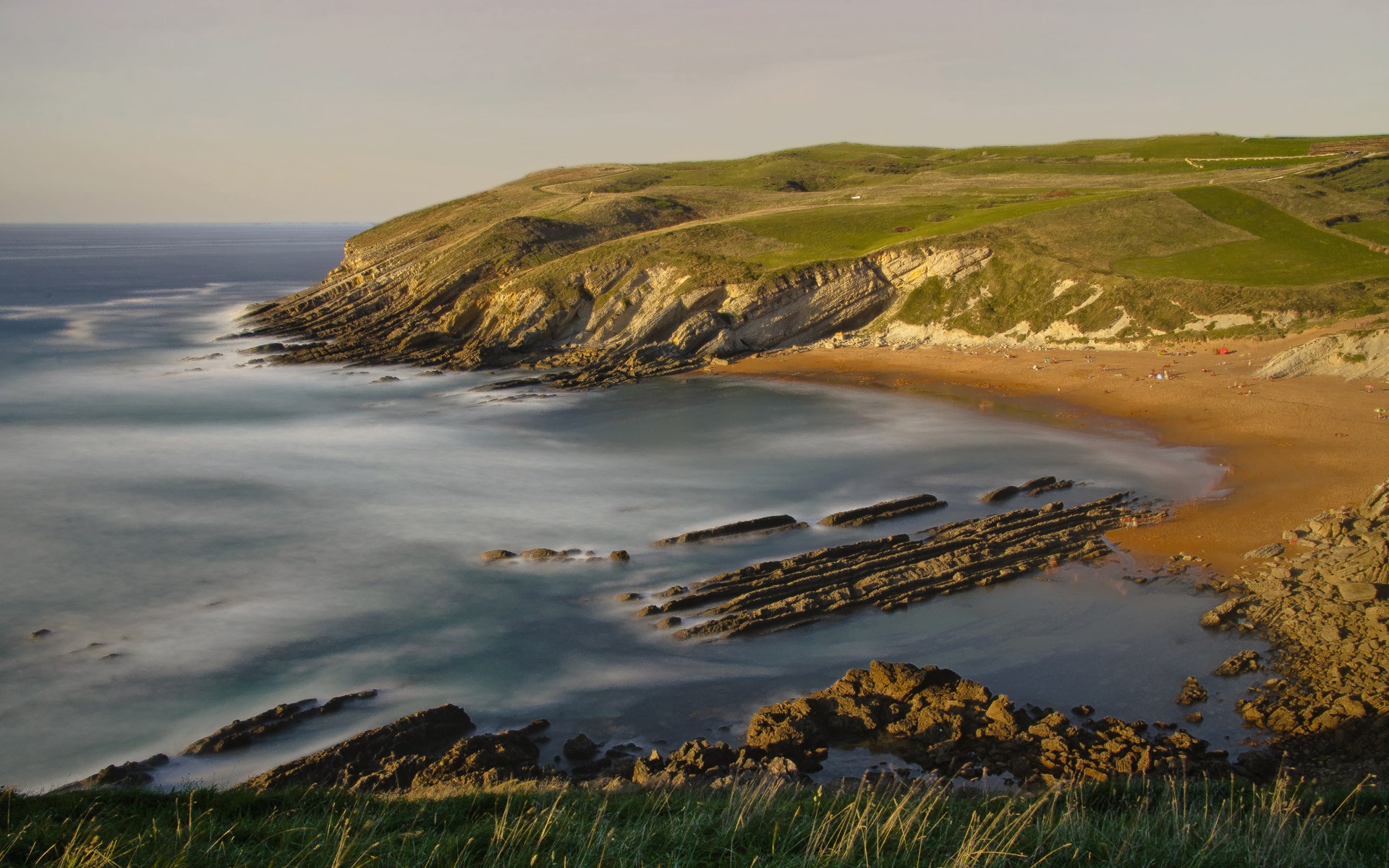 Coastal cliffs and beach with long exposure ocean waves HD Wallpaper