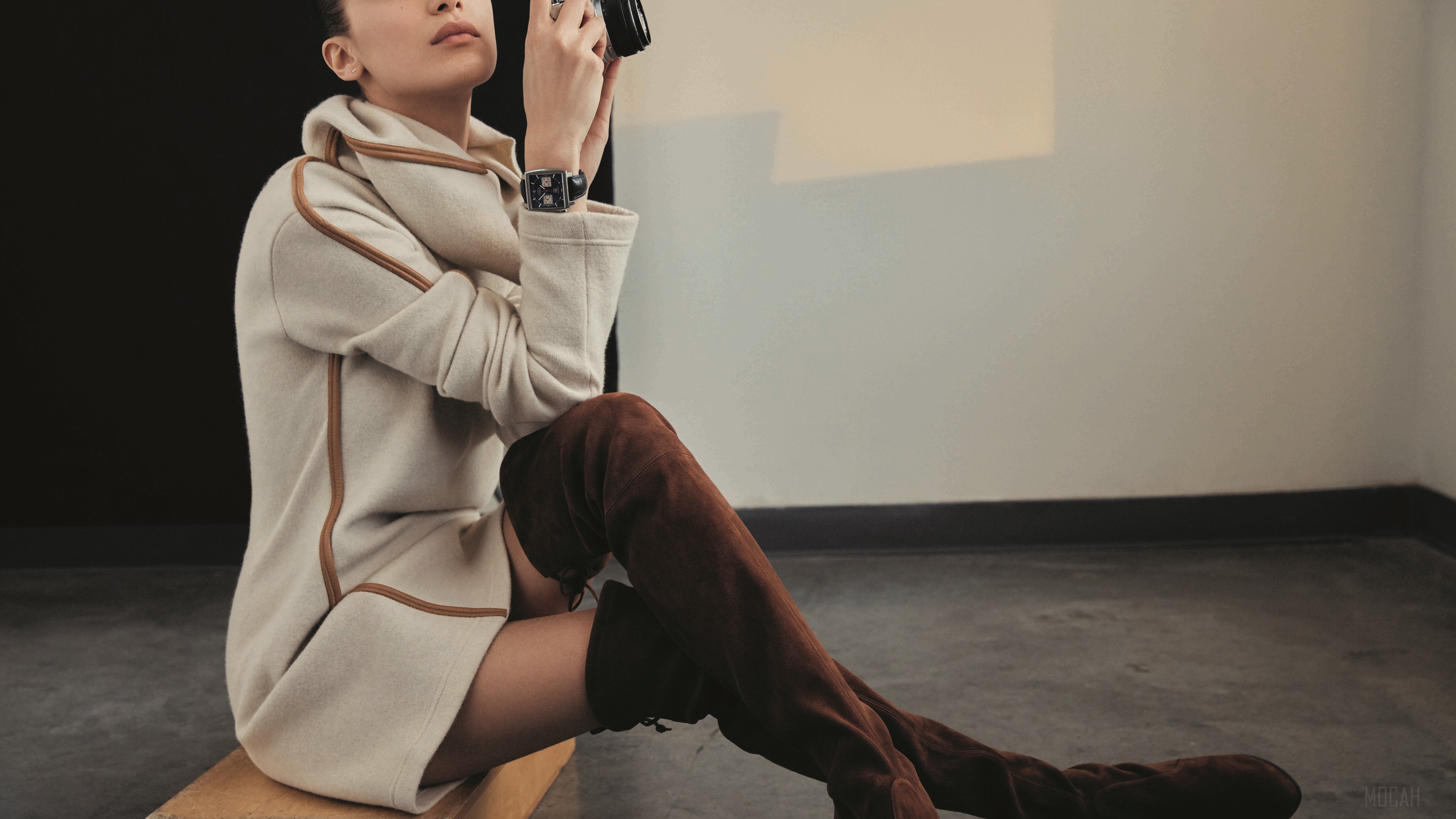 Bella Hadid wearing a coat and boots, holding a camera HD Wallpaper