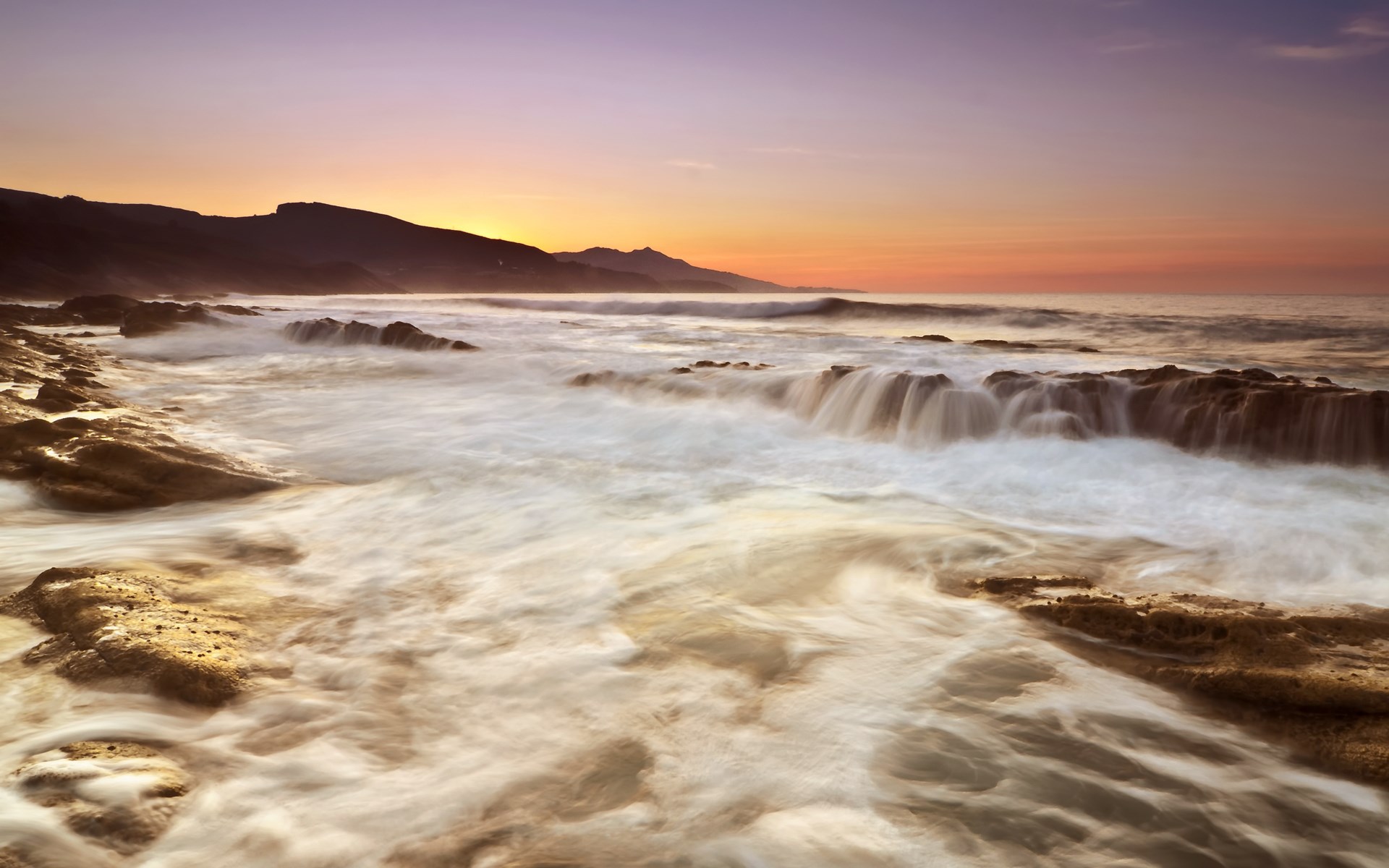 Ocean waves crashing on rocky shore at sunset HD Wallpaper