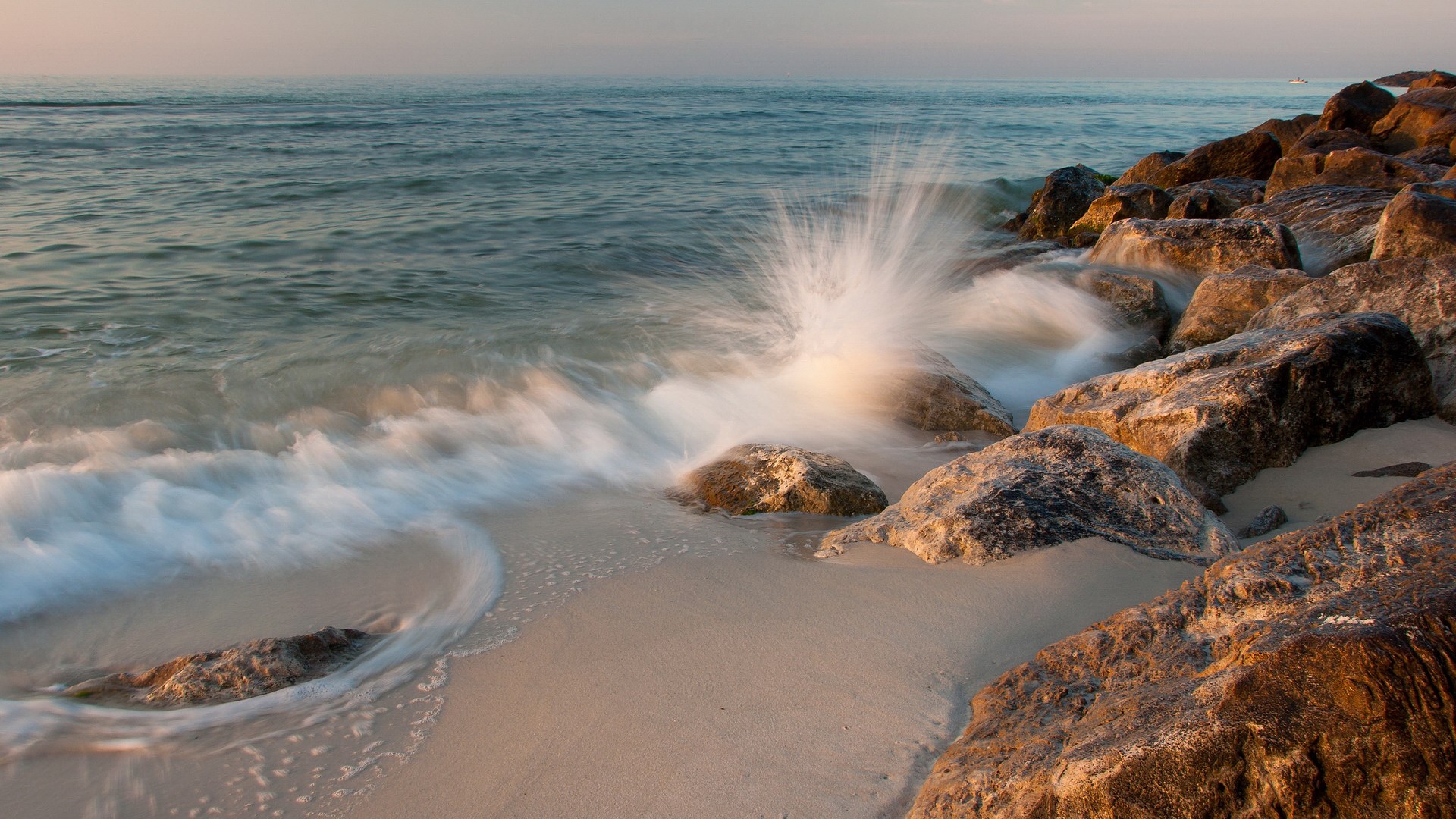 Waves crashing on rocks at a beach HD Wallpaper