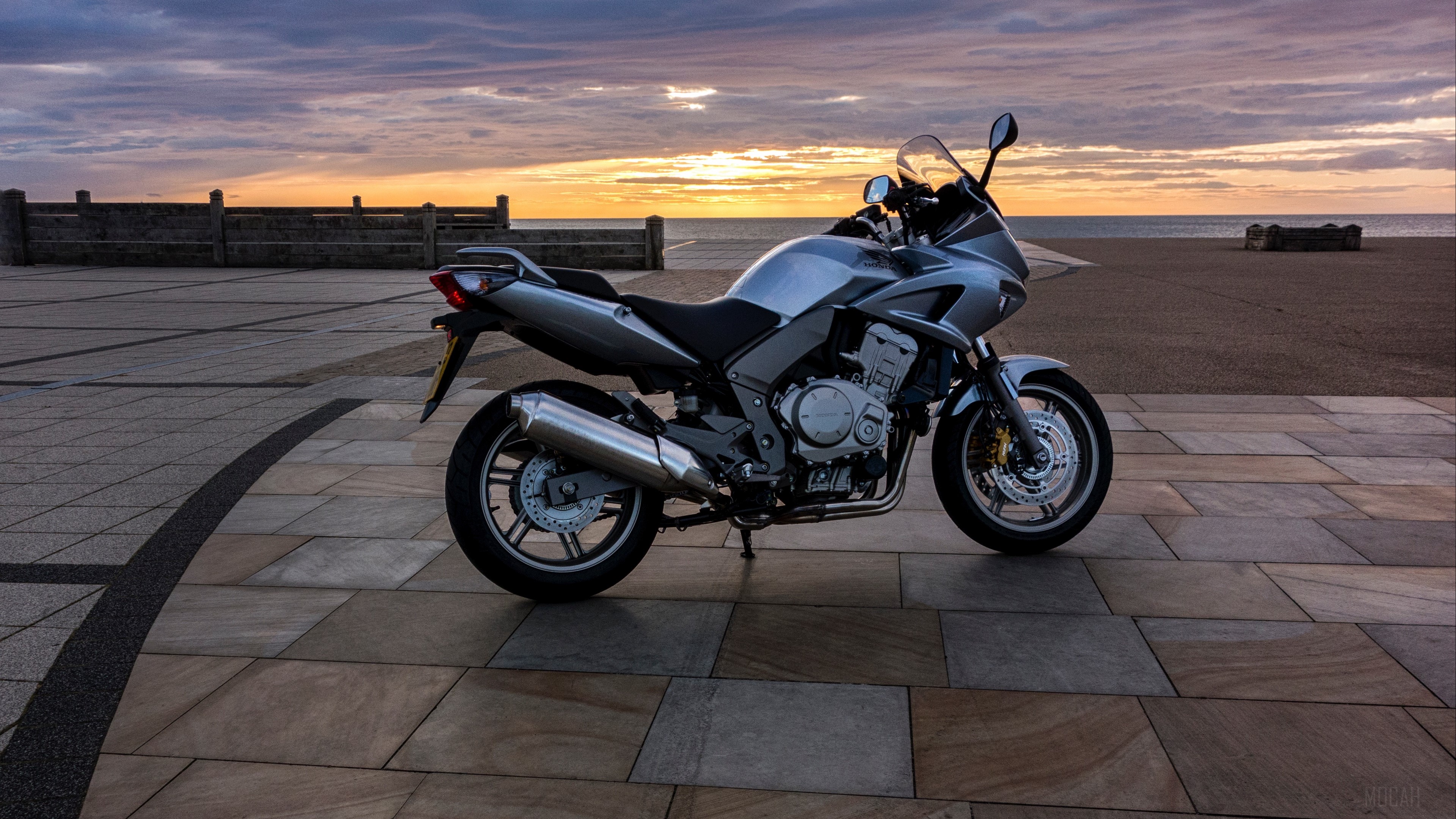 Silver Honda motorcycle parked by the sea at sunset HD Wallpaper