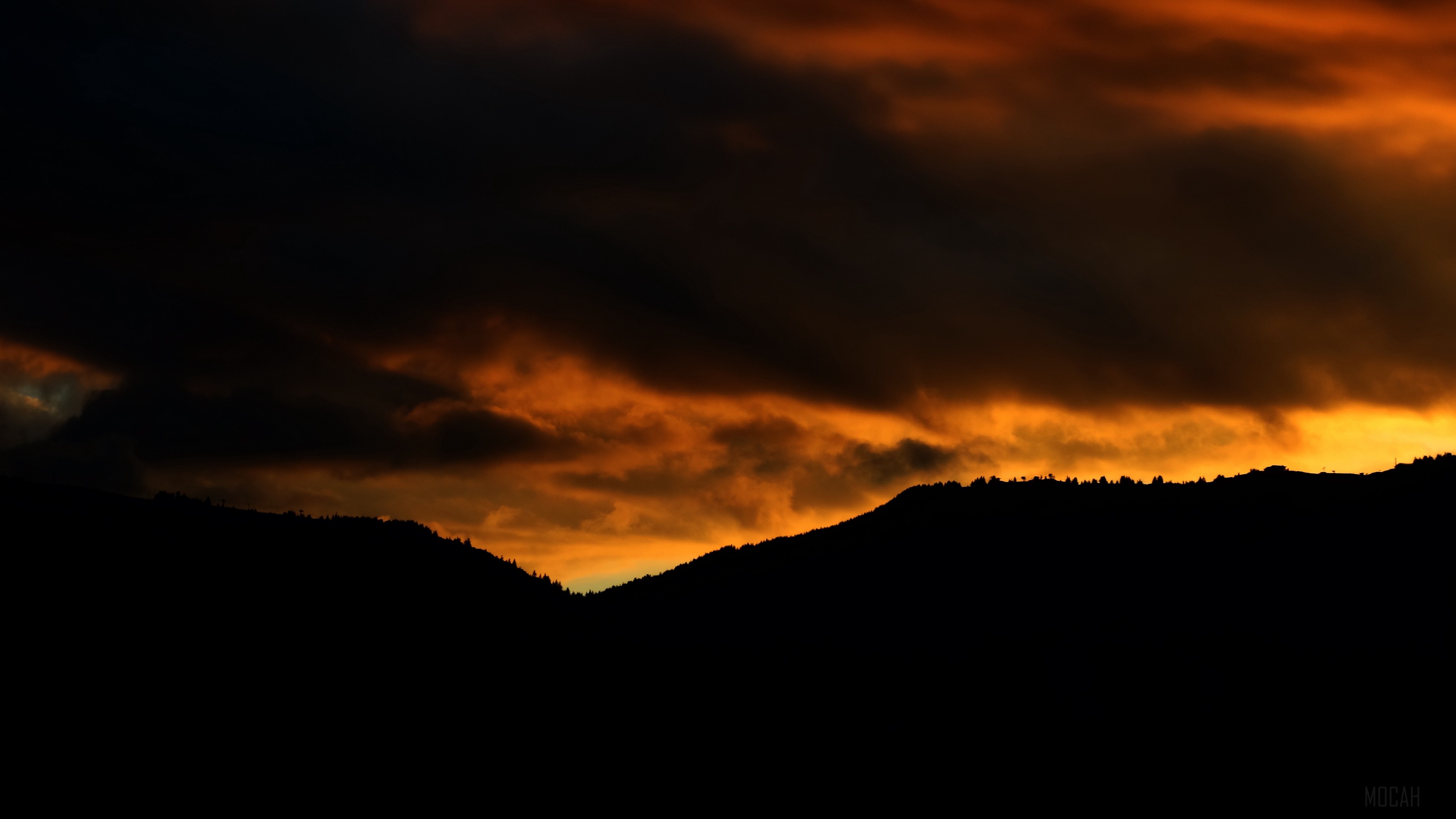 Sunset over silhouetted mountains with dramatic clouds HD Wallpaper