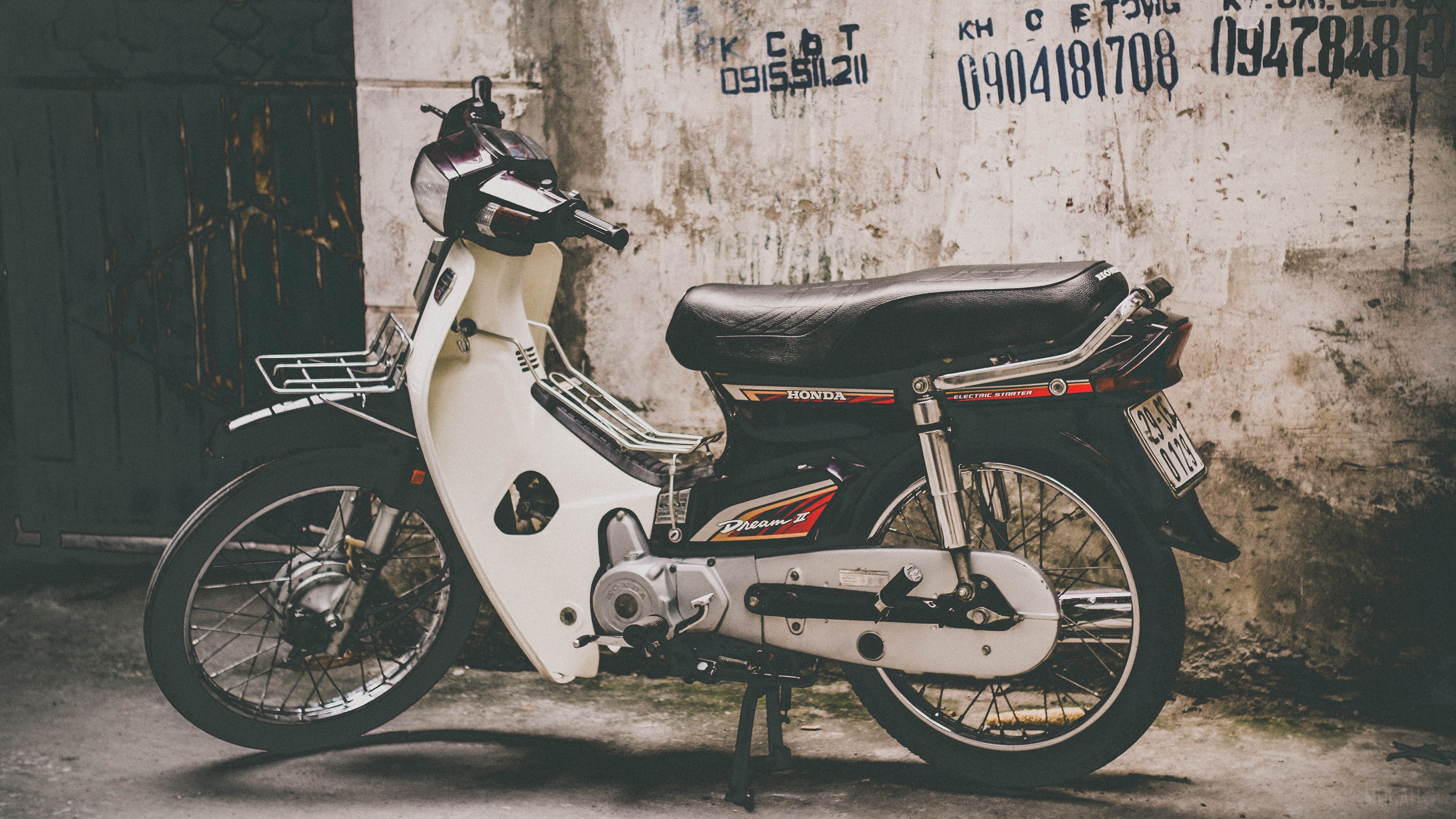 Honda Dream II motorcycle parked against a textured wall HD Wallpaper