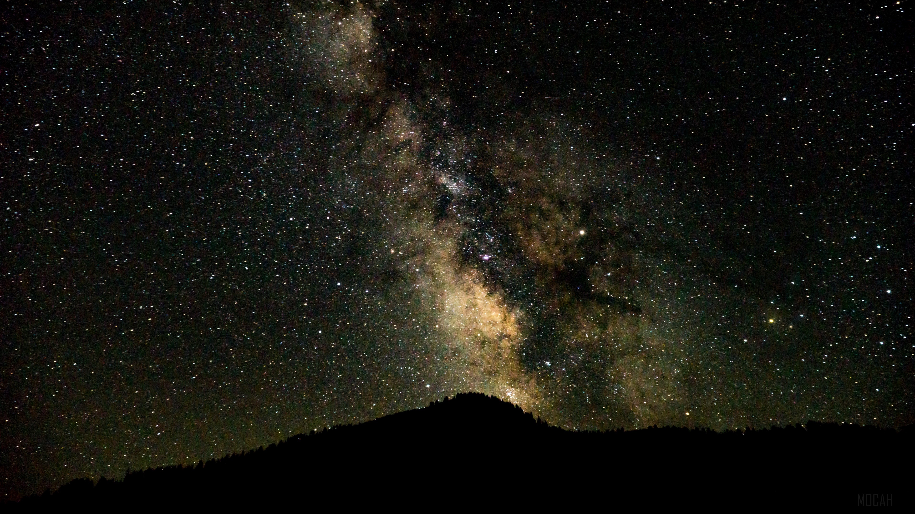 Starry night sky with the Milky Way over a silhouetted mountain HD Wallpaper