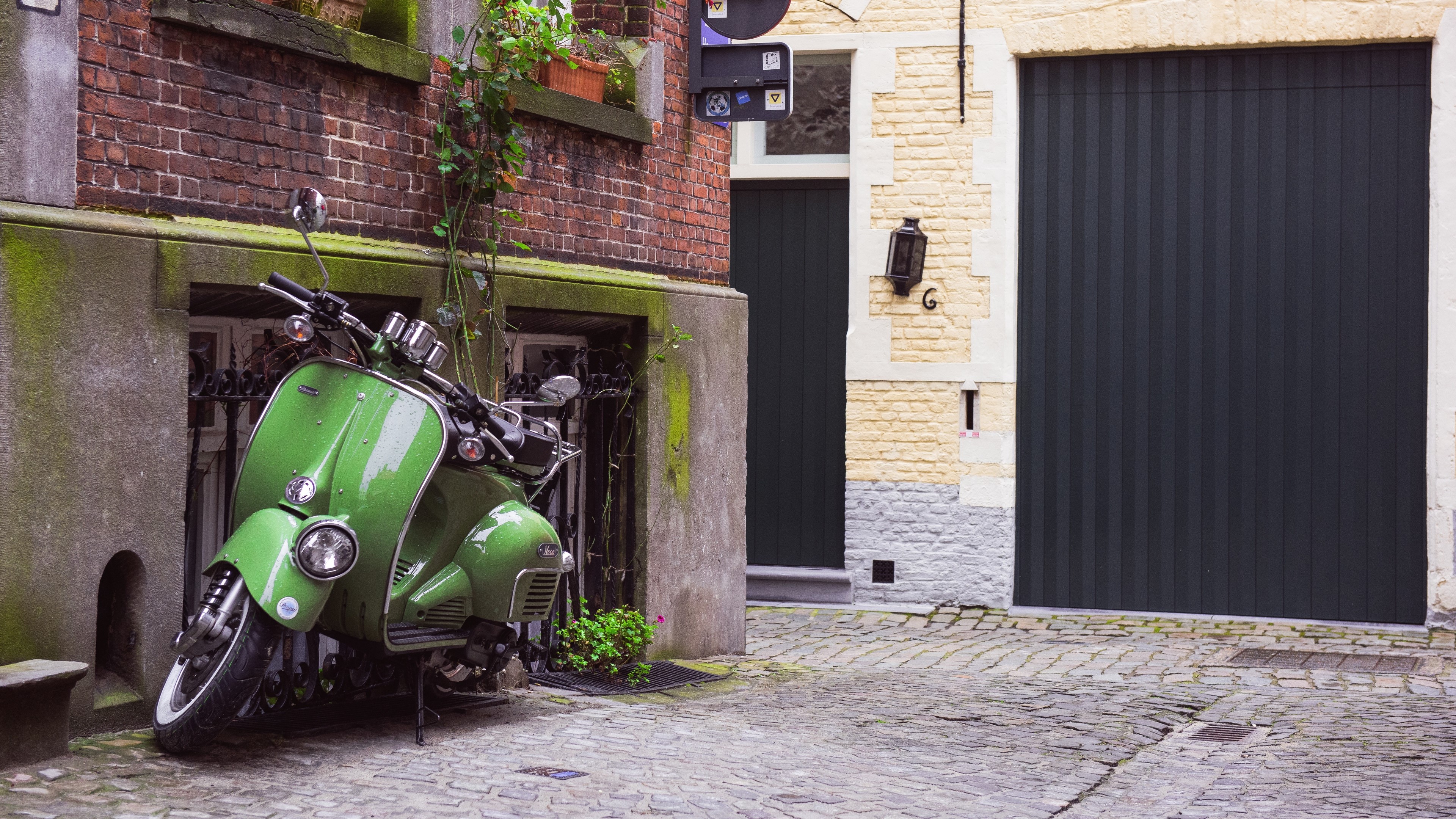 Green scooter parked in a cobblestone alley HD Wallpaper