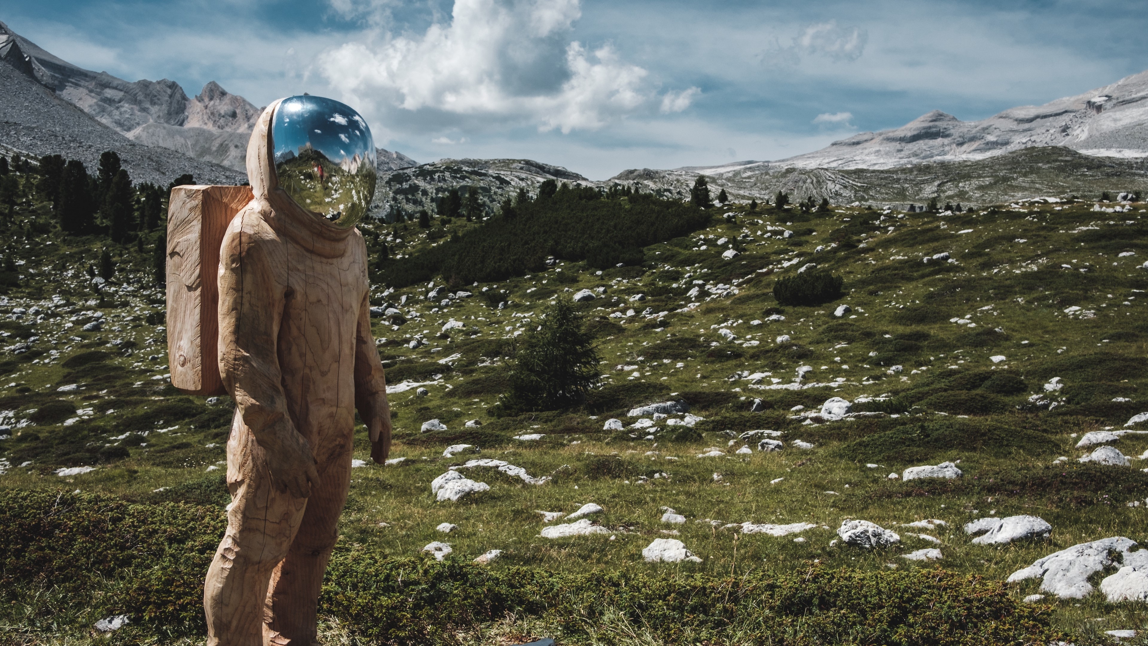 Wooden cosmonaut sculpture in a mountain landscape 4K HD Wallpaper